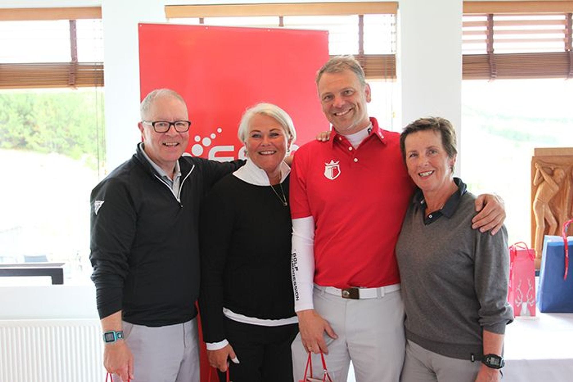 Two men and two women smiling for the camera and standing in front of a promotional banner