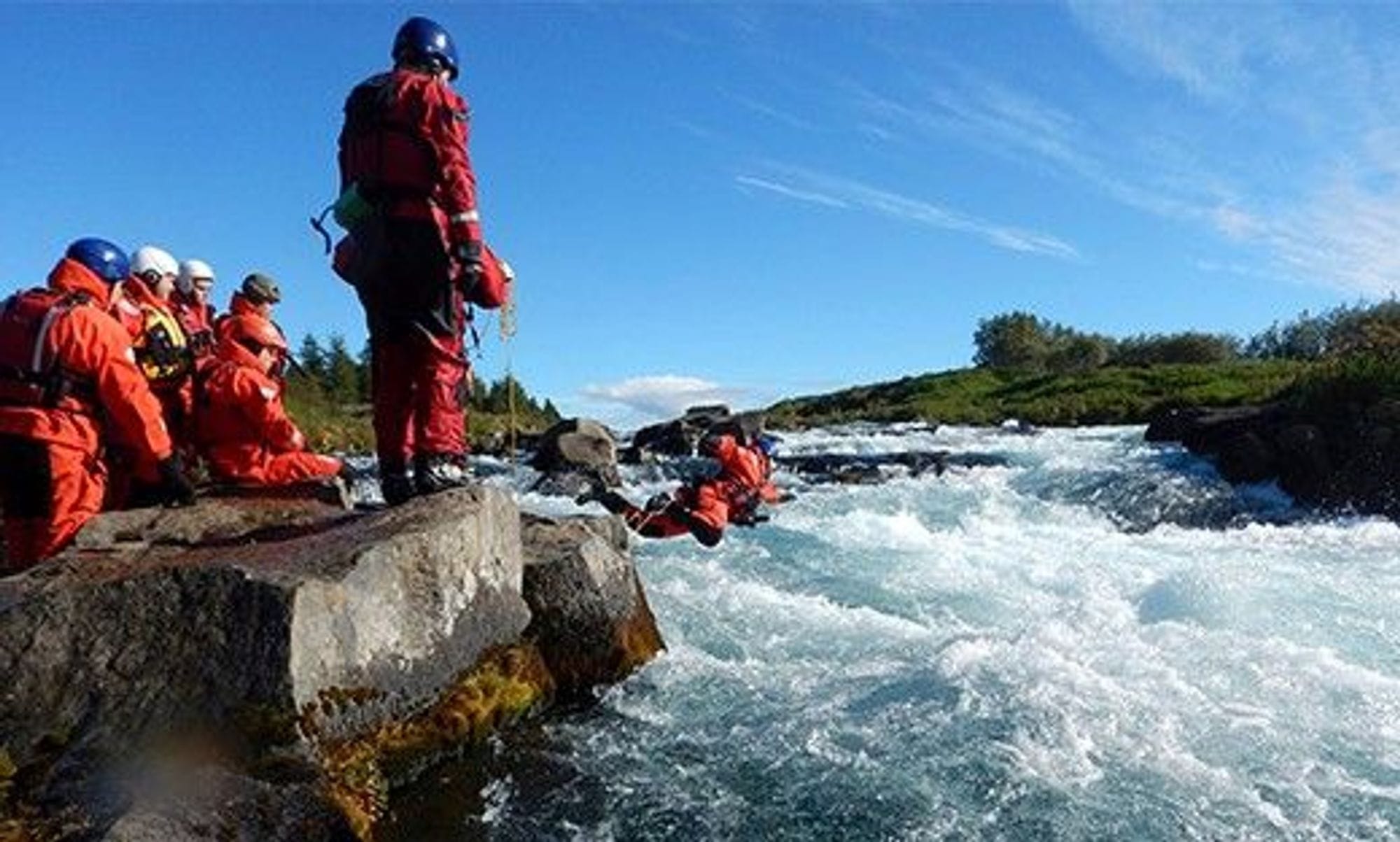 Fólk í flotbúningum vinnur að björgun í á.