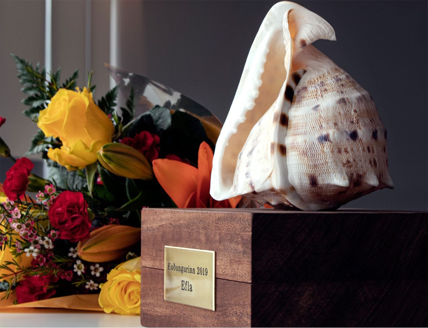 An award resembling seashell with bouquet of colorful flowers next to it