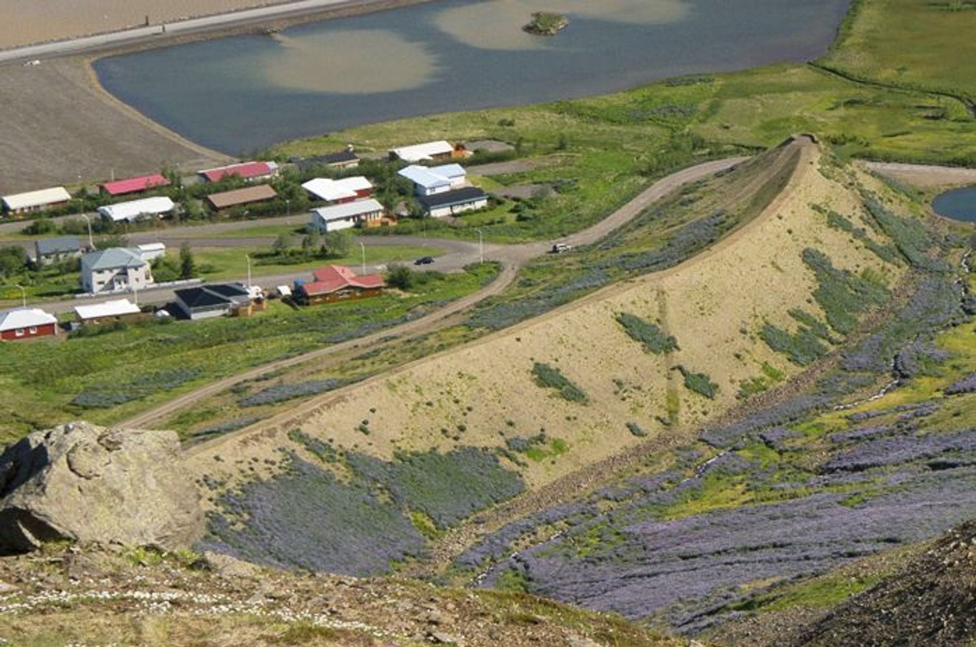 landscape of hilly terrain with various shades of brown and green and a rural settlement