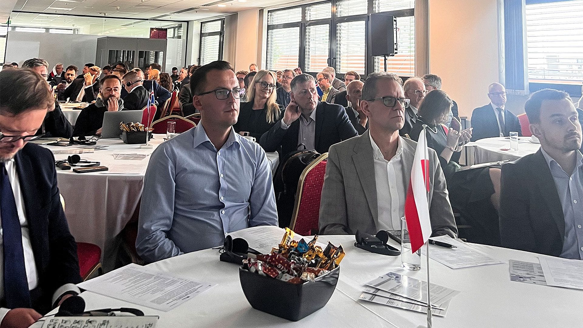 A conference setting with numerous attendees seated around round tables