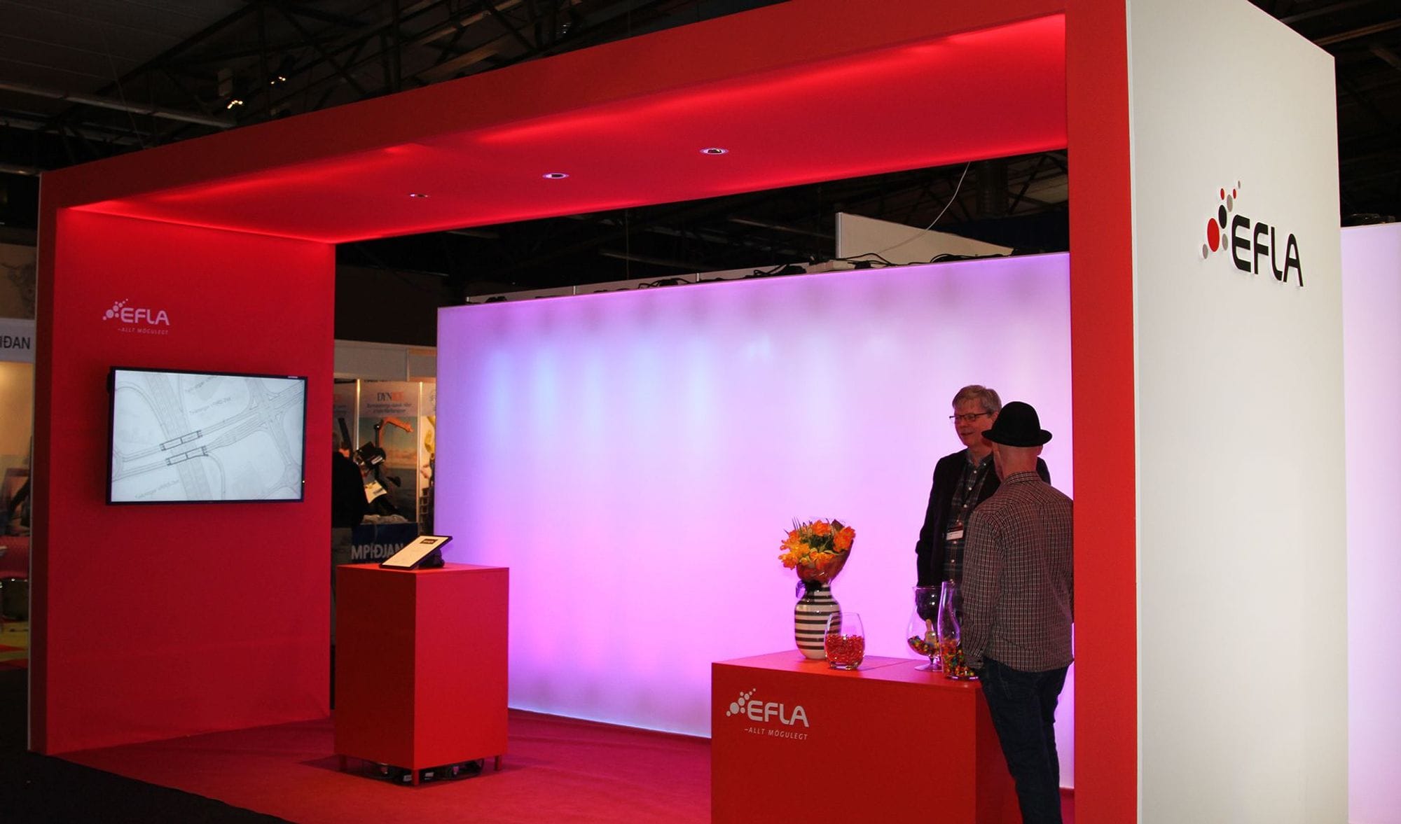 two men standing in a bright red promotional booth