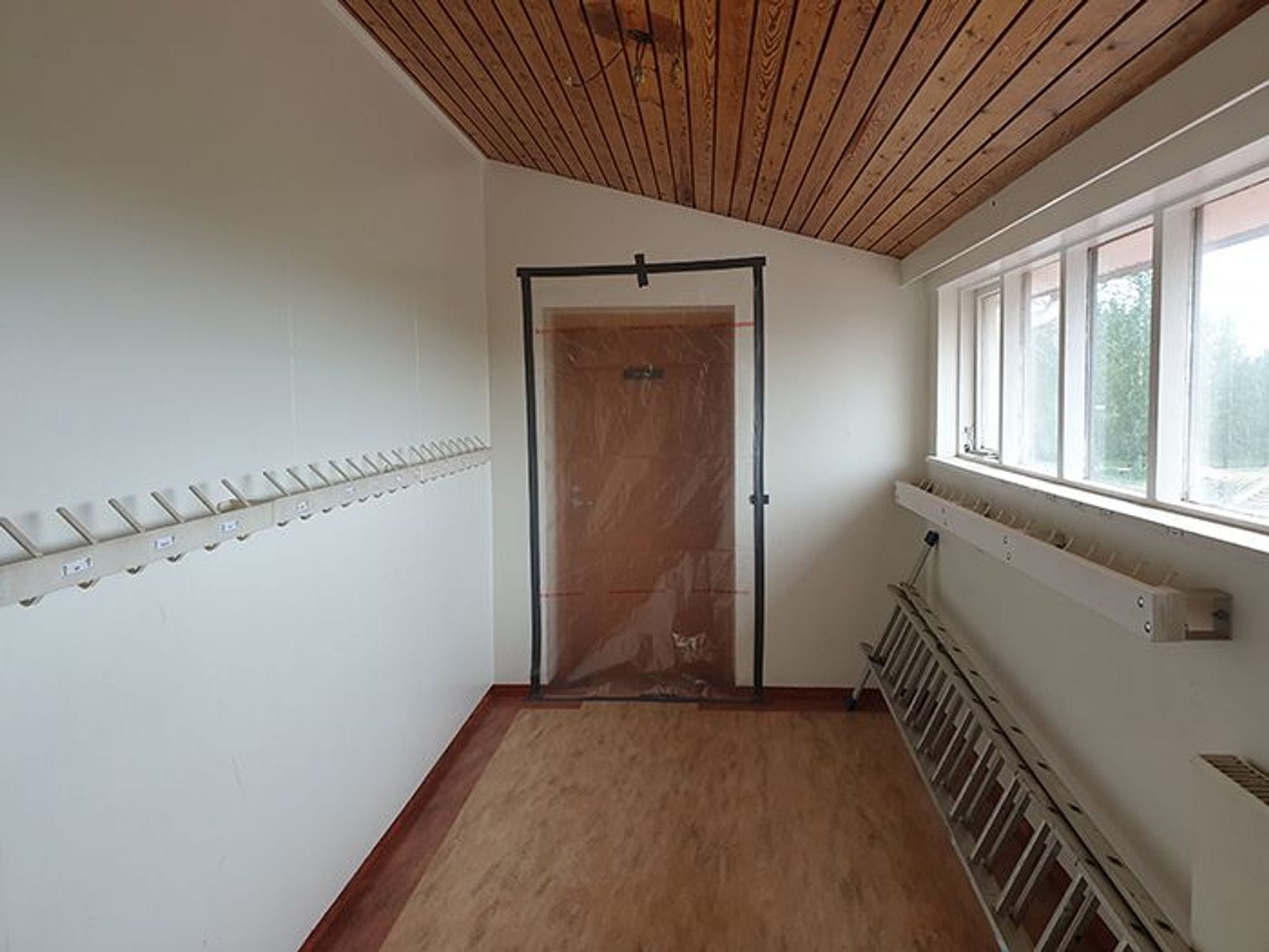 A small empty with wooden floor, ceiling and door and small windows