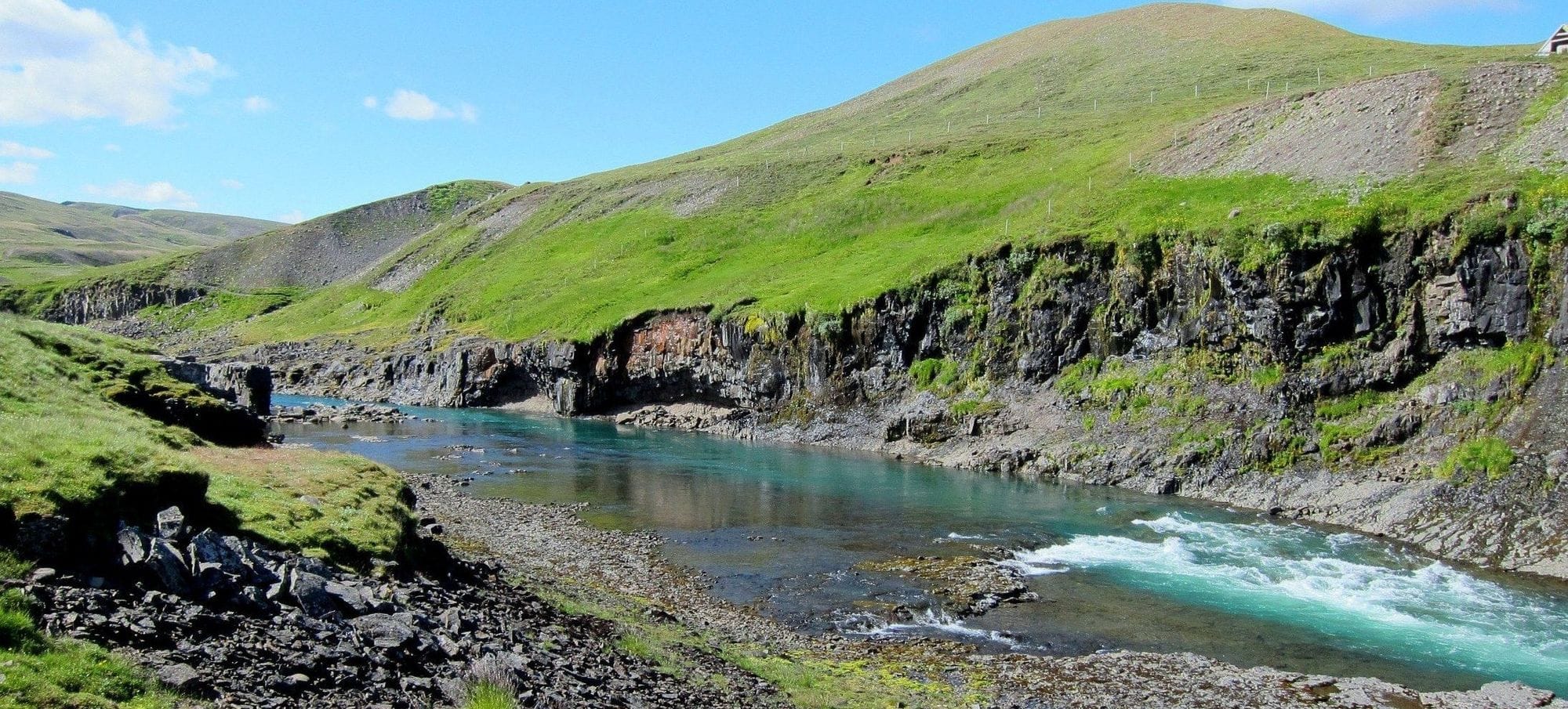 Á rennur meðfram fjalli.
