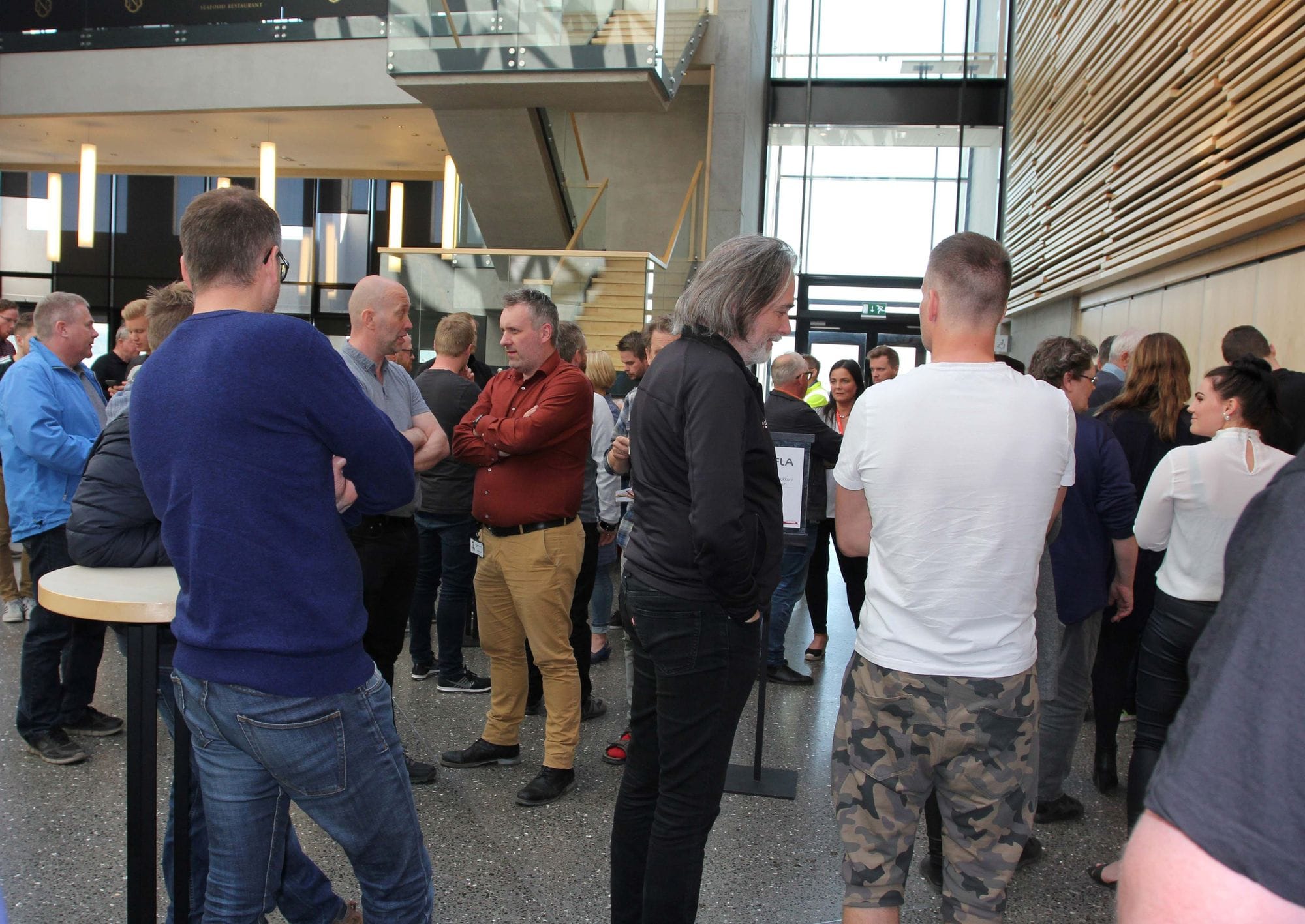 A group of people mingling and having conversation in a spacious hall