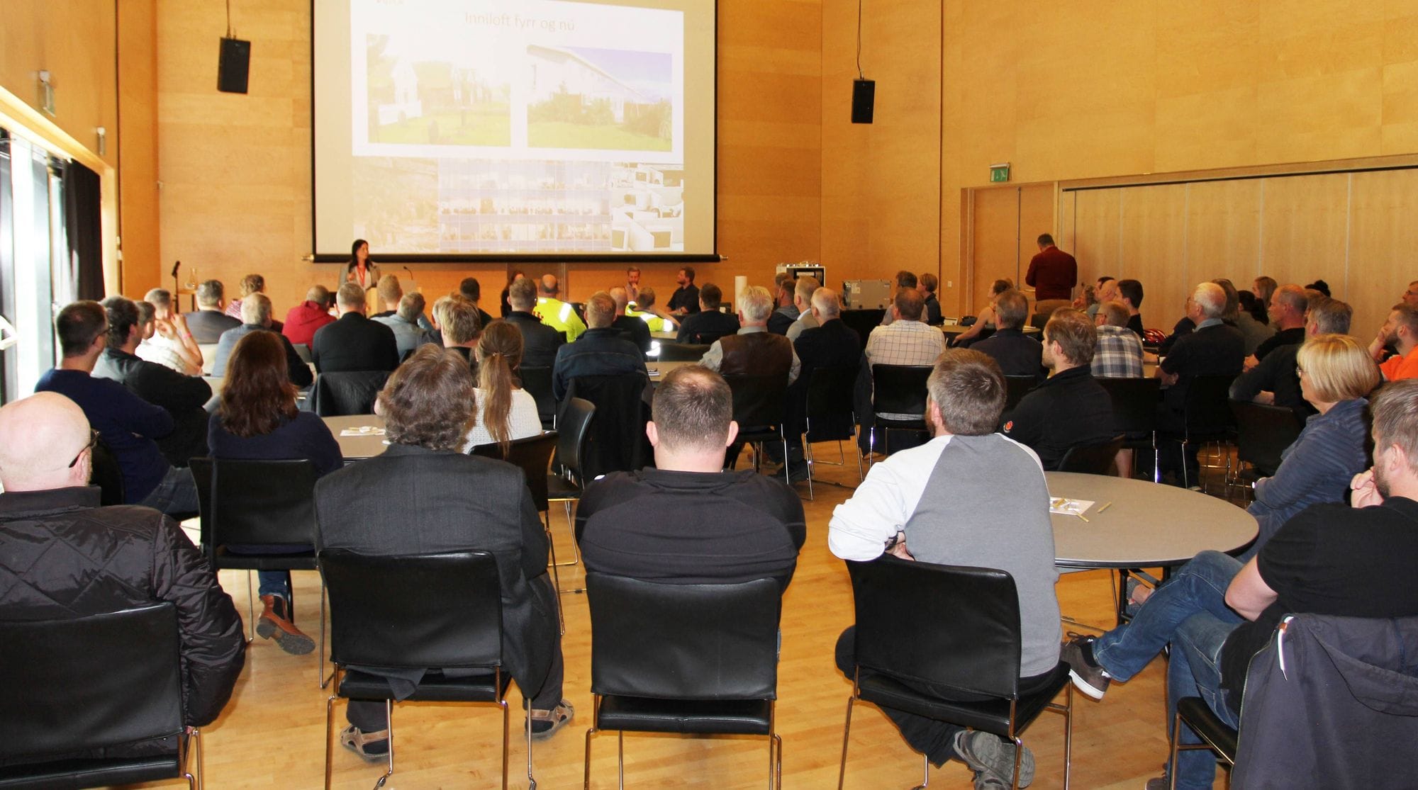 A group of people seated in a conference room looking towards the speaker and at the front