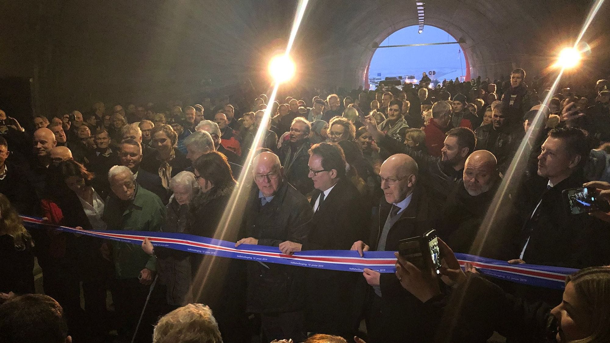 A group of people gathered inside a tunnel waiting for ribbon-cutting ceremony