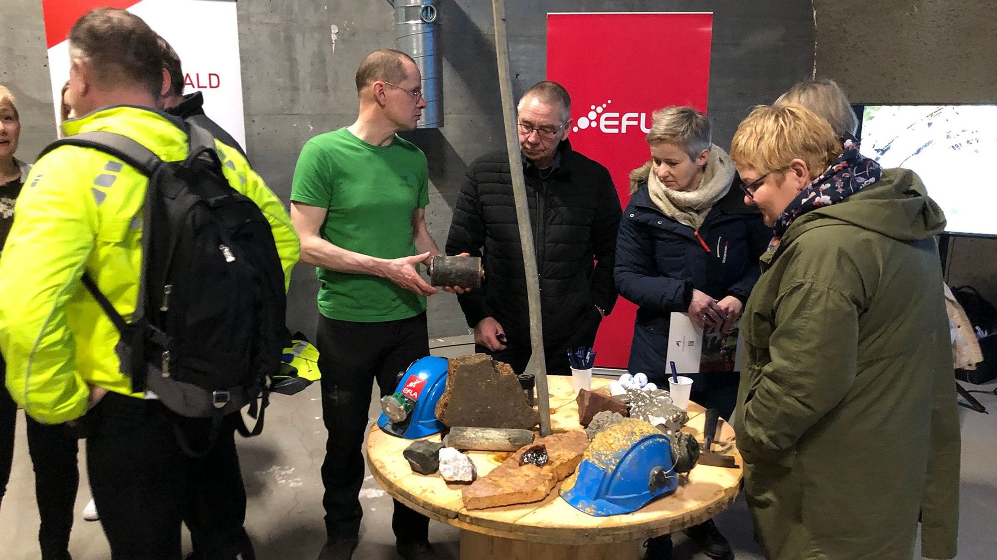 A group of people gathered around a round table with various items on display