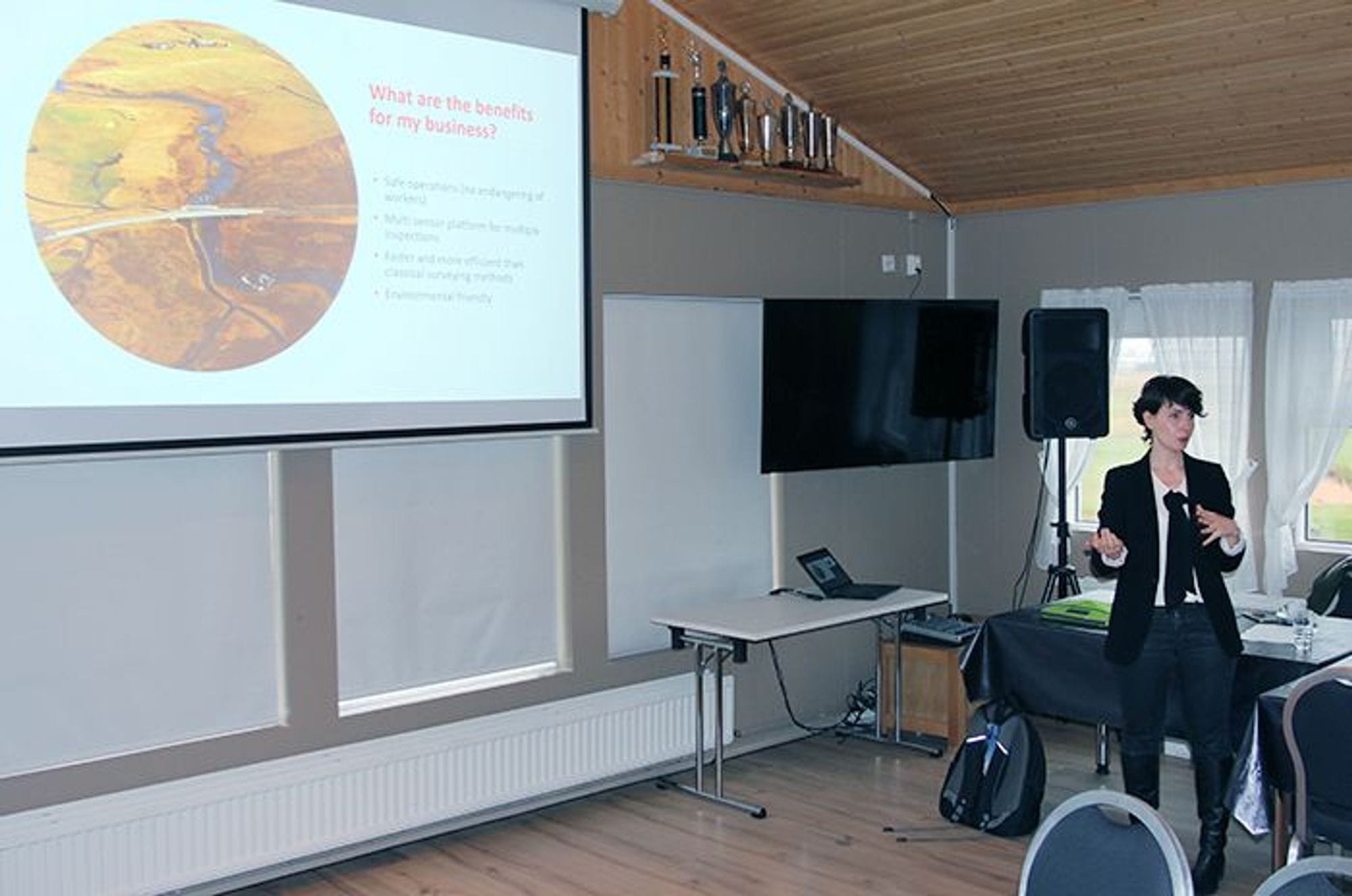 A person presenting next to the slide about benefits for the business
