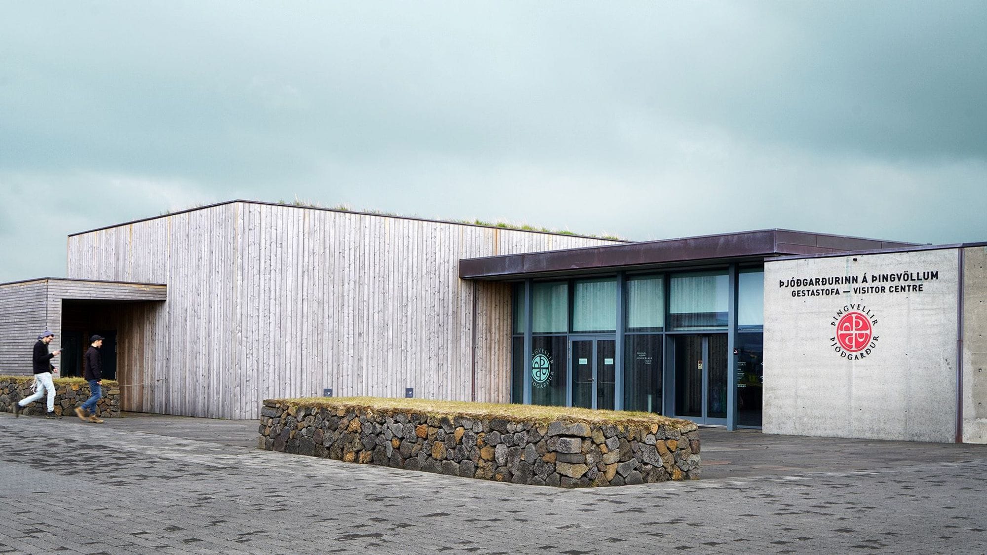 Ljósmynd af Gestastofu þingvallam viðarklædd bygging, hellulagt fyrir utan.
