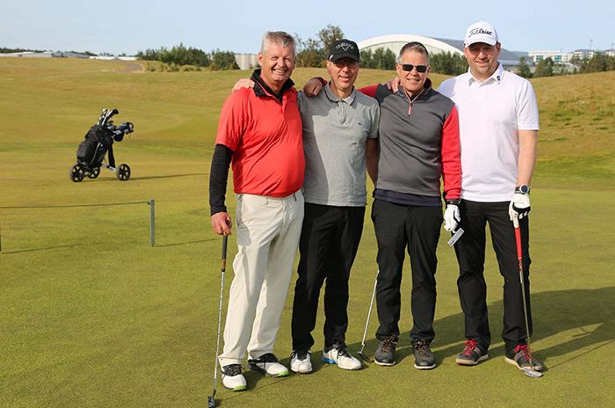 Four men posing on a golf course