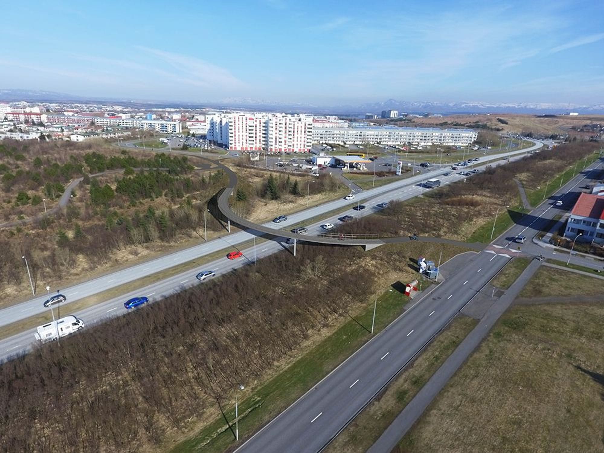 A road intersection with cars and pedestrian bridge 