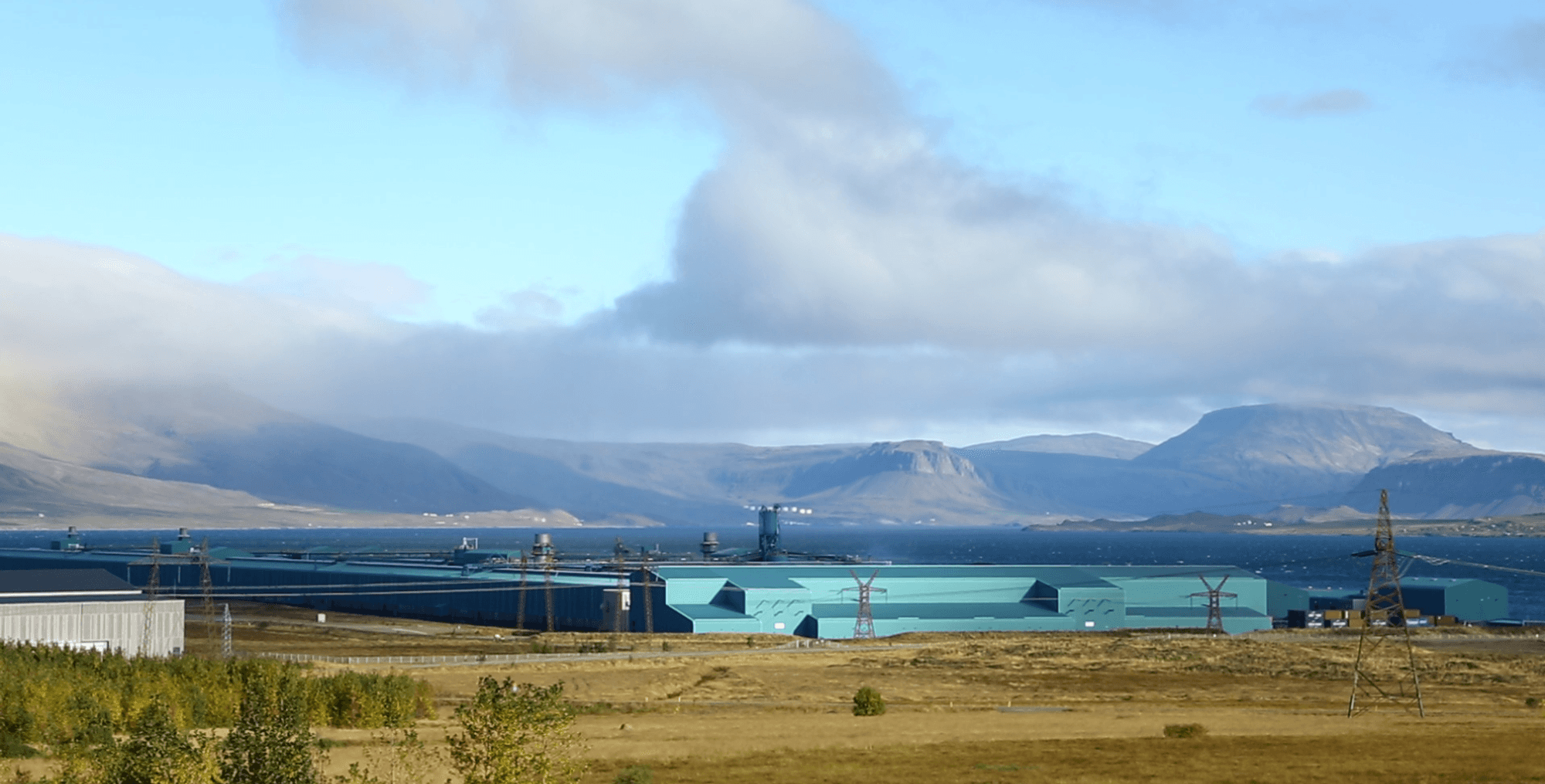 Virkjun með fjöll í baksýn.