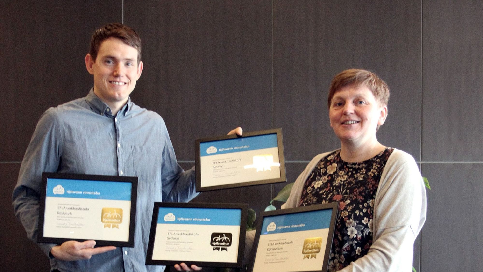 Two individuals holding four framed certificates 