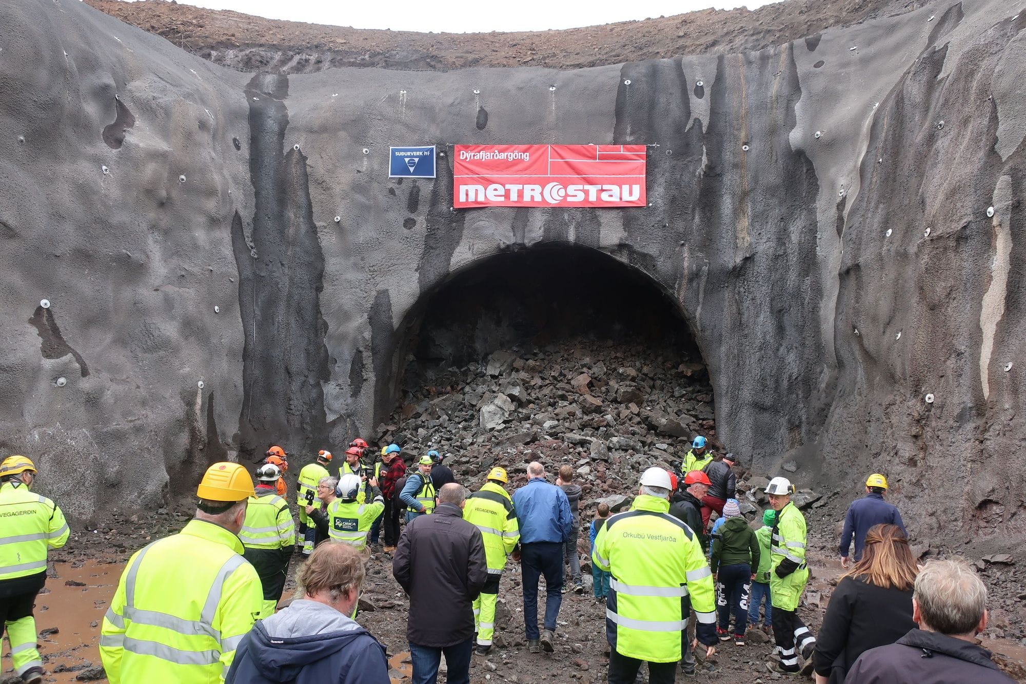 A group of people wearing high visibility jackets, gathering at the entrance of a large tunnel
