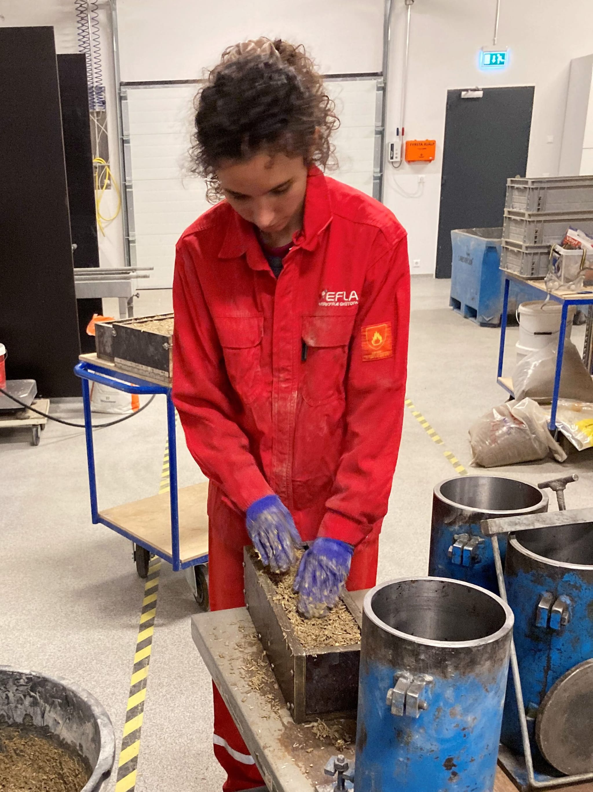 Starfsmaður EFLU í rauðum vinnugalla mótar hampsteypu í mót