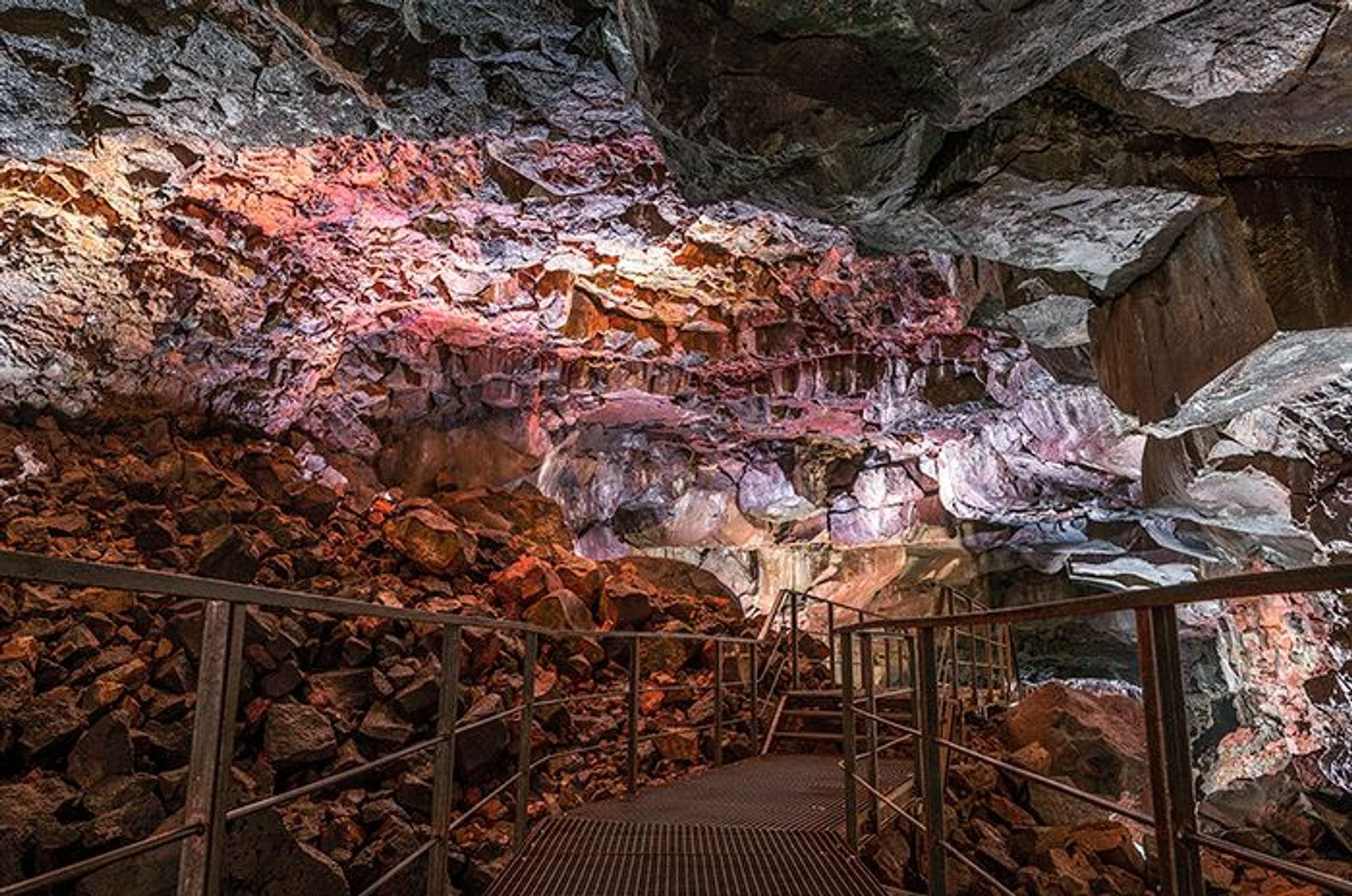 metal stairs leading towards red stone wall in a cave