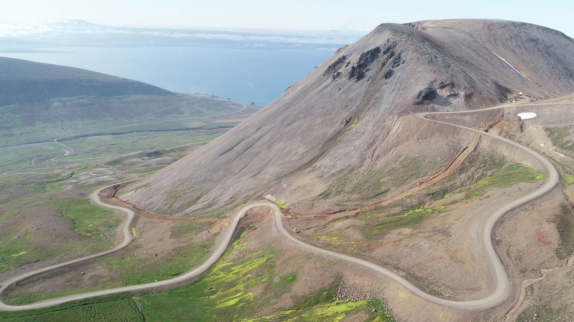A winding mountain road with steep turns, leading to a peak