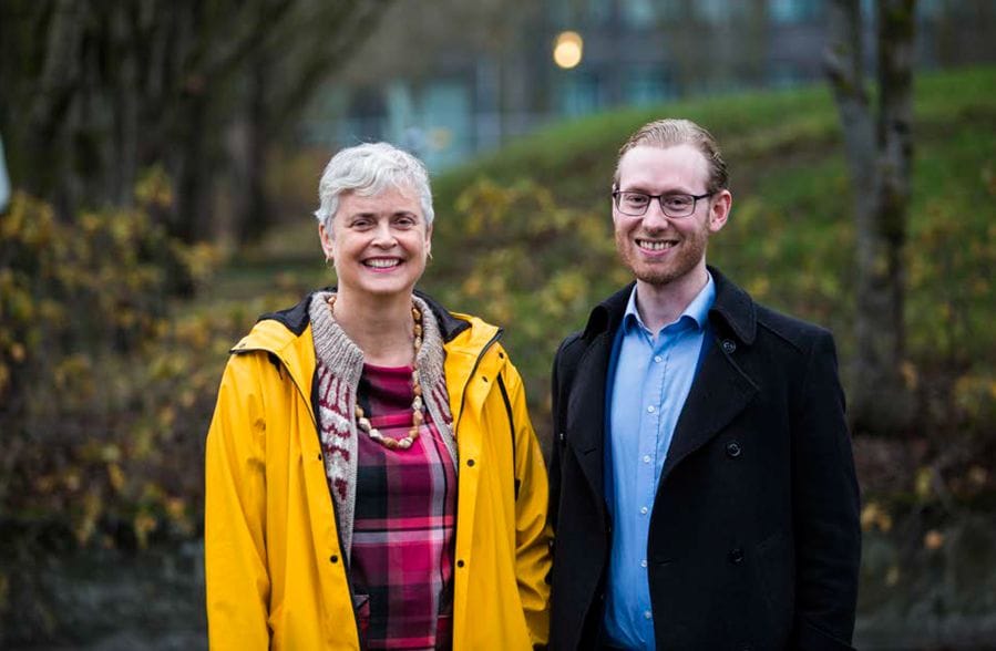A woman wearing a bright yellow jacket, standing next to a man wearing black coat