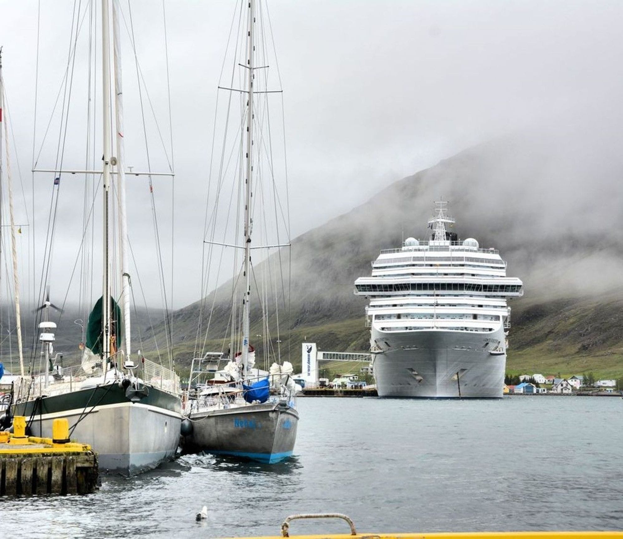 A large cruise ship docked near a coast and two small boats