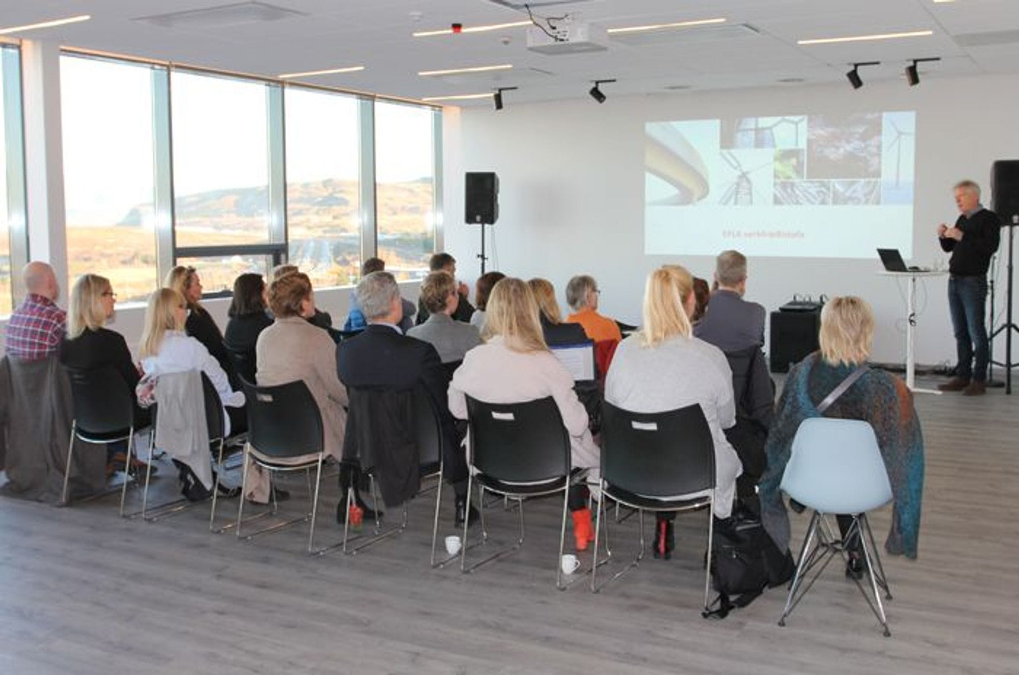 An audience seated in rows listening to a speaker at a presentation 
