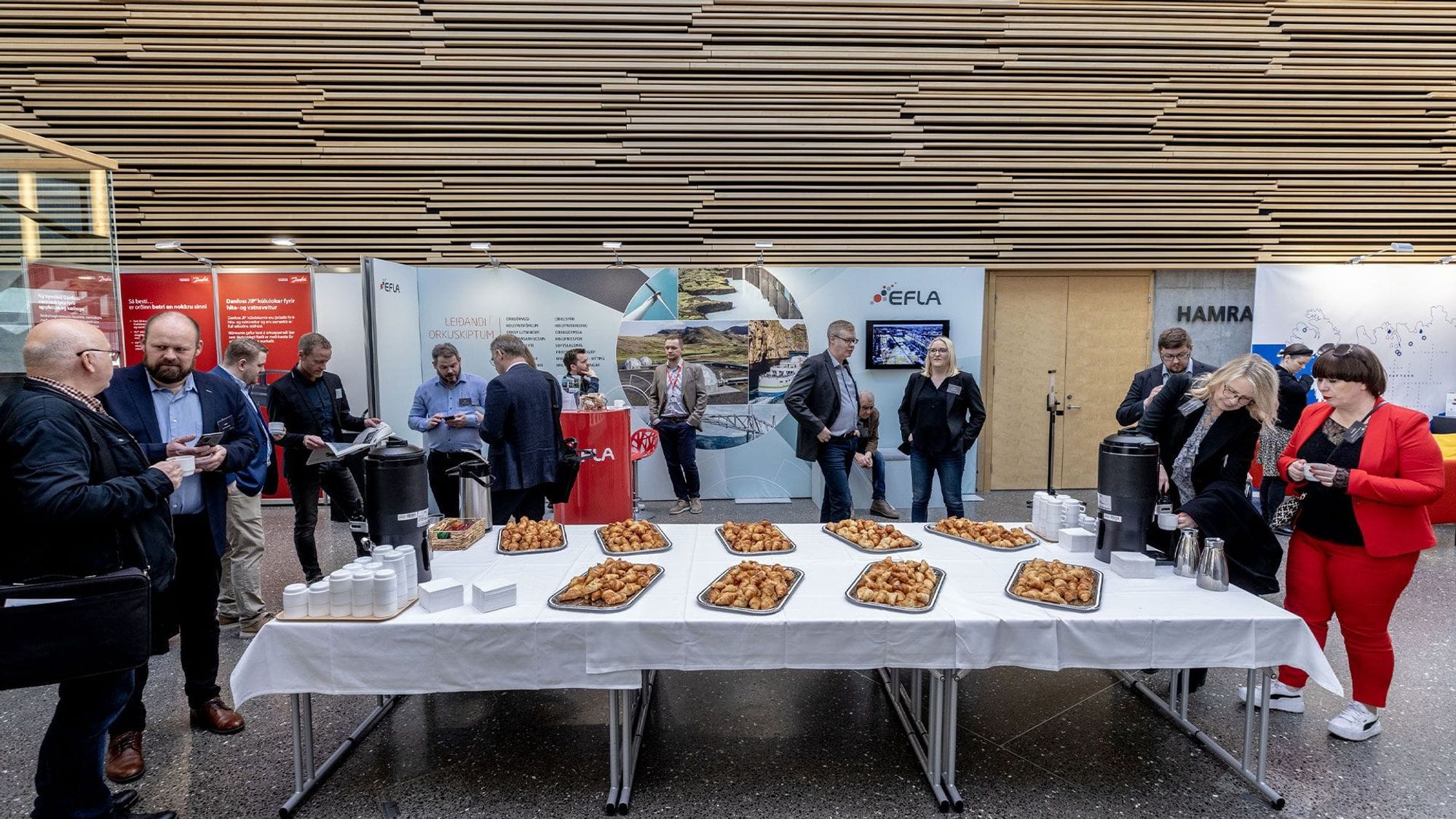 People standing around a table laden with food and drinks with promotional materials visible in the background