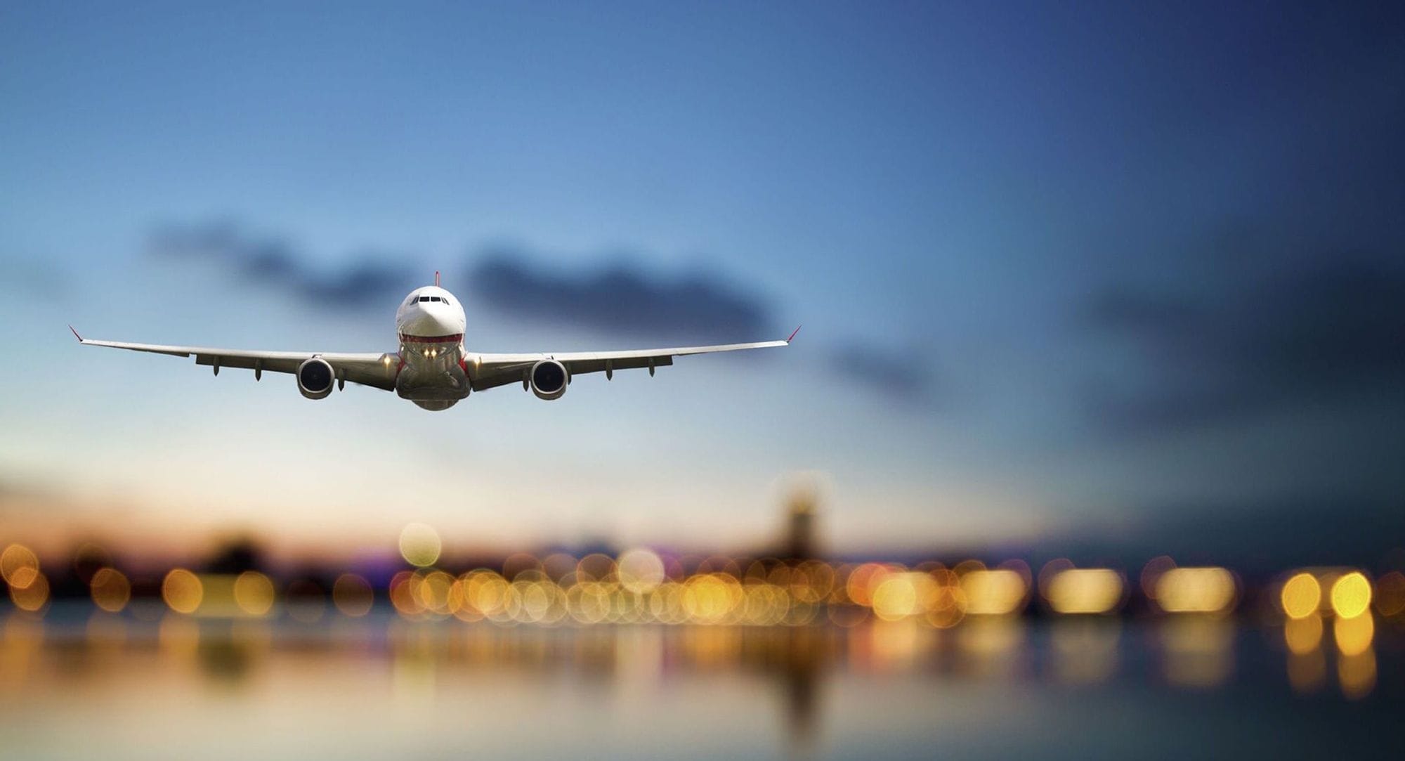 An airplane in flight with blurred lights of a cityscape in the background
