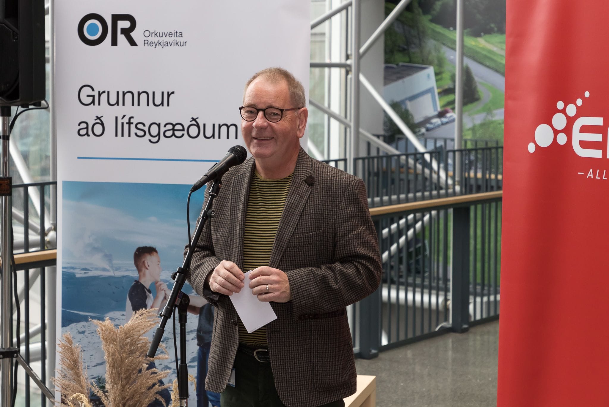 A man speaking into a microphone in front of promotional banners
