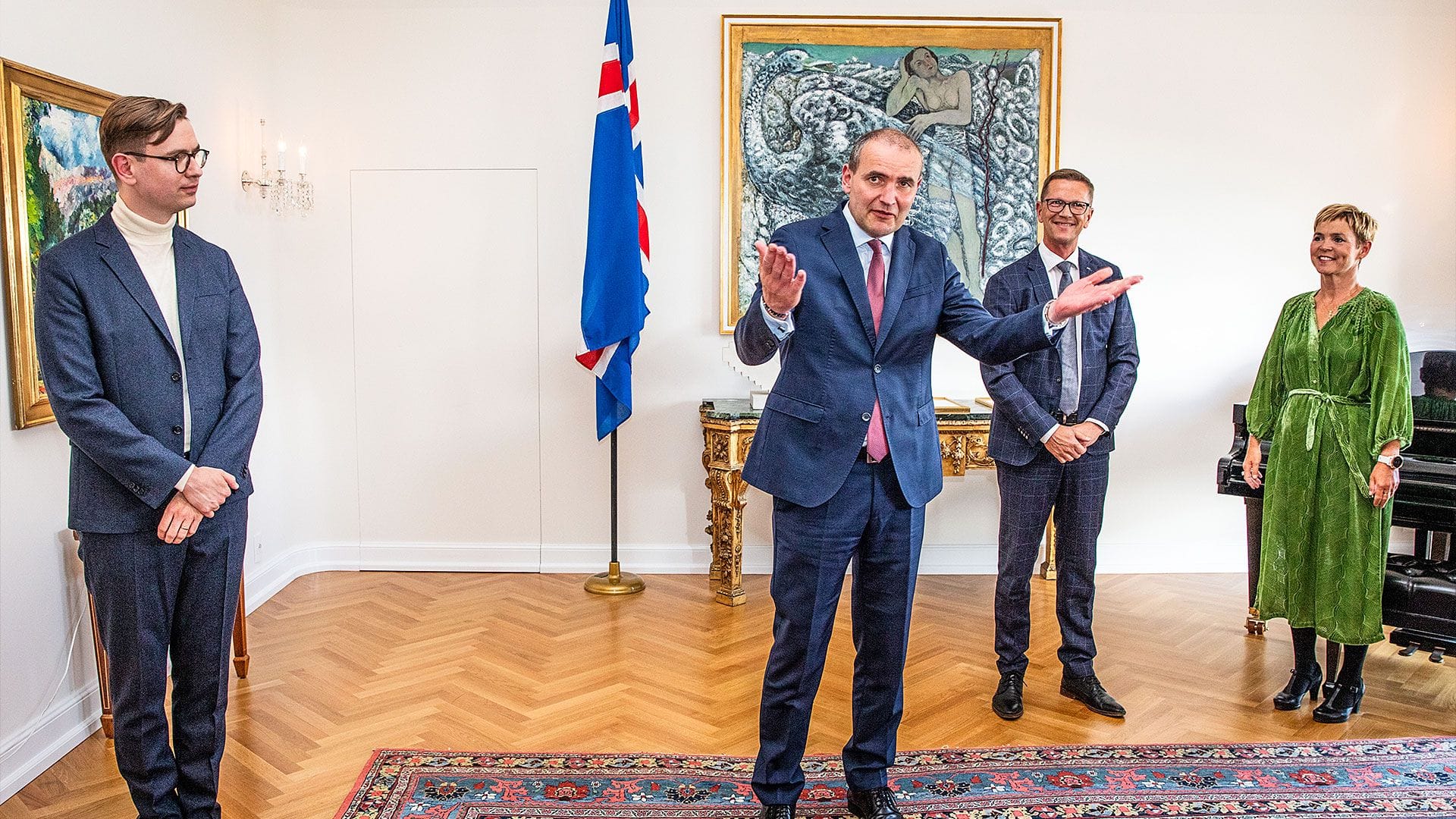 A man in blue suit gesturing with his hands while other three individuals observing him
