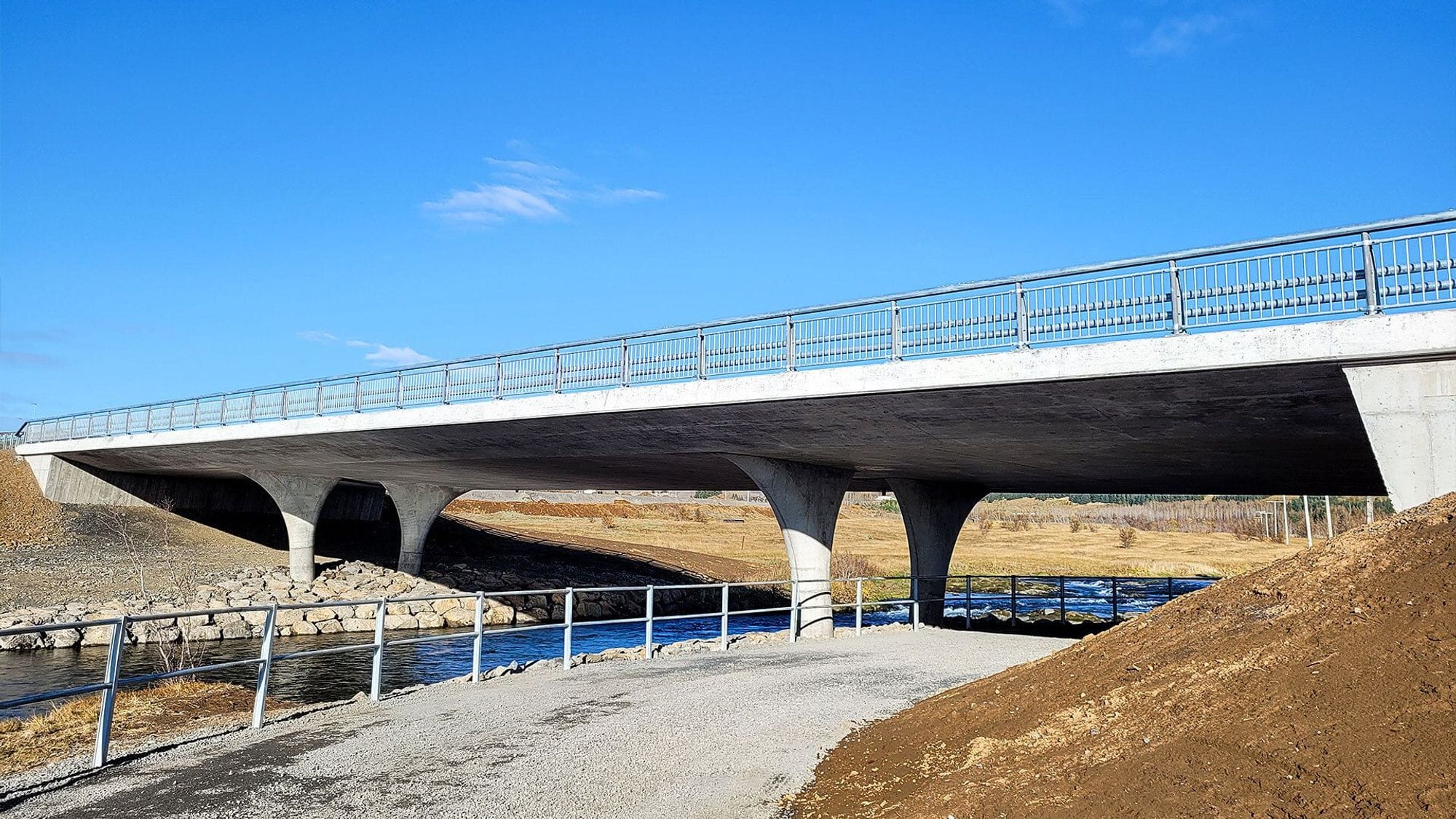 A concrete bridge with metal railing over a waterway