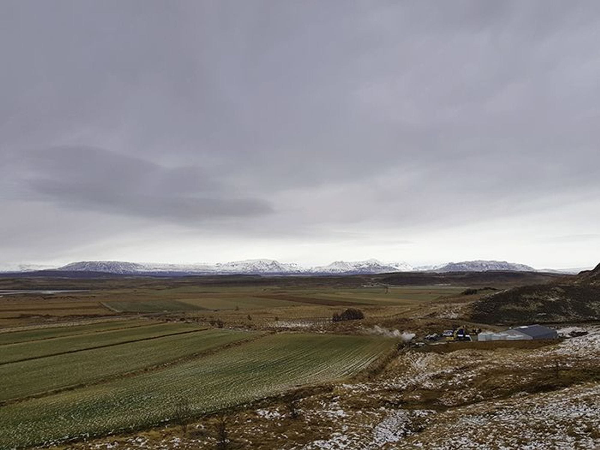 A rural landscape with green field and snowy mountain 
