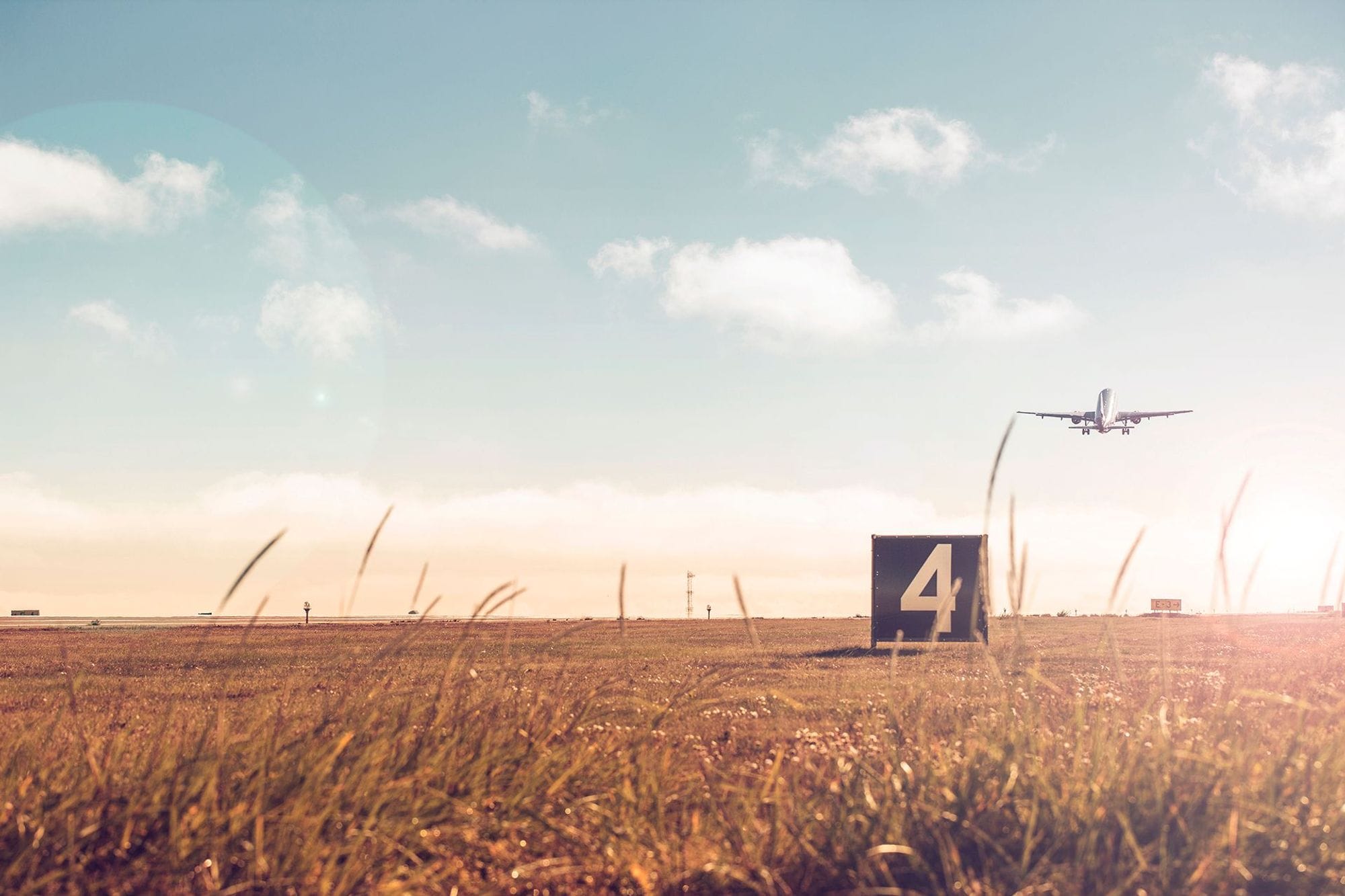 A field with an airplane in the sky 