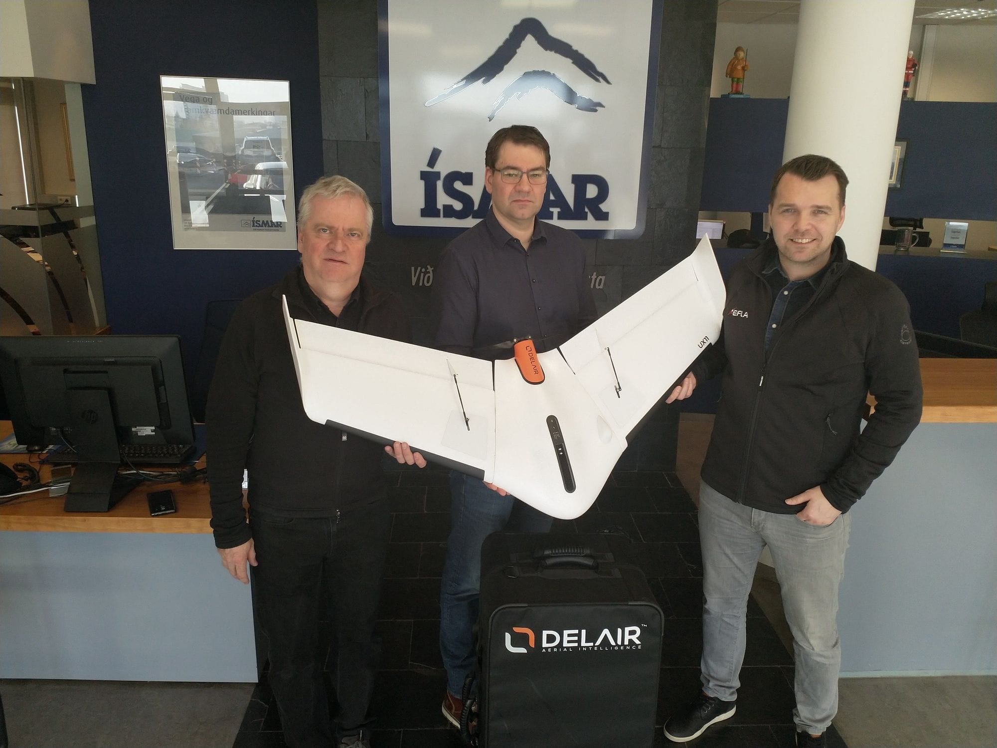Three men posing with a white airplane model 