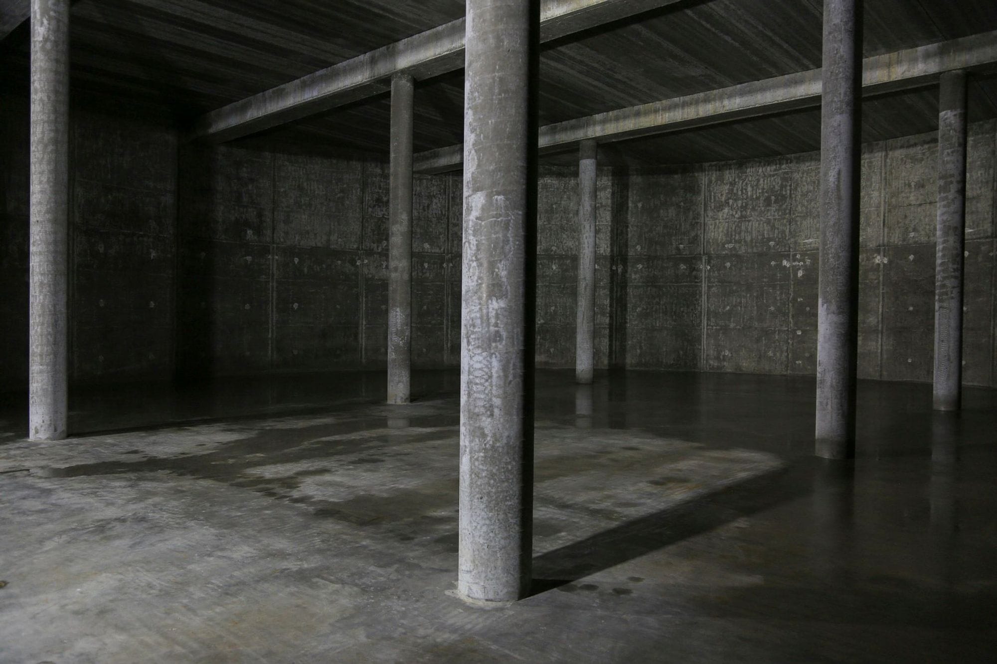 A dimly lit concrete space with pillars