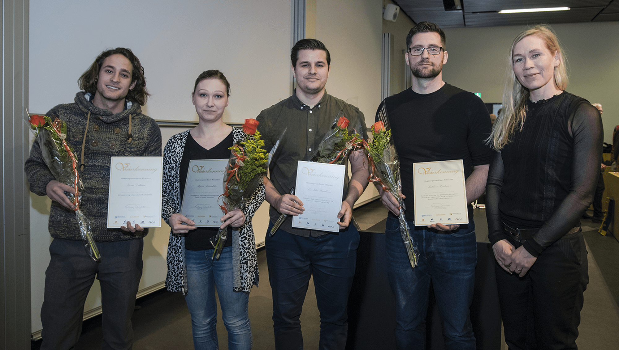 A group of people standing together, holding flowers and certificate