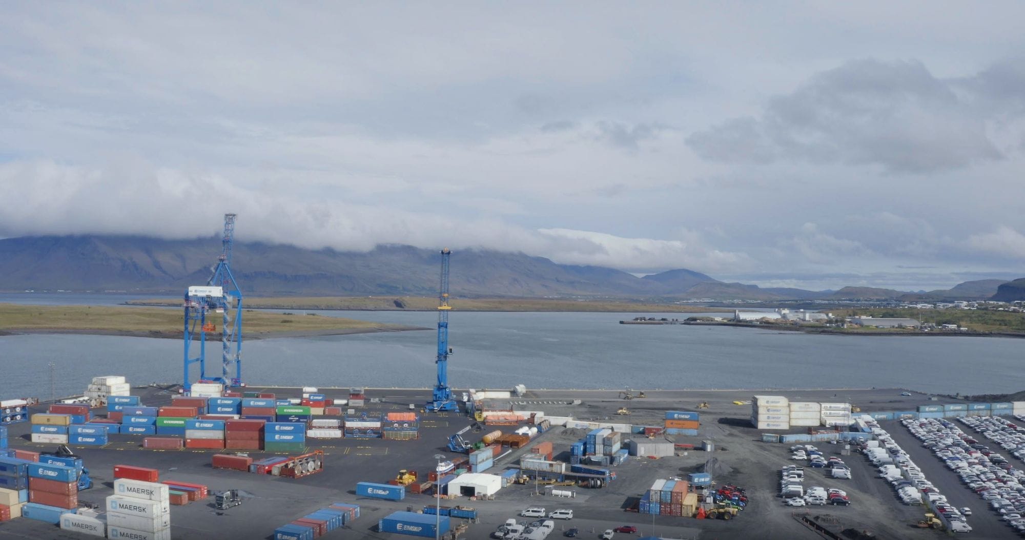 A busy port area with shipping containers and cars