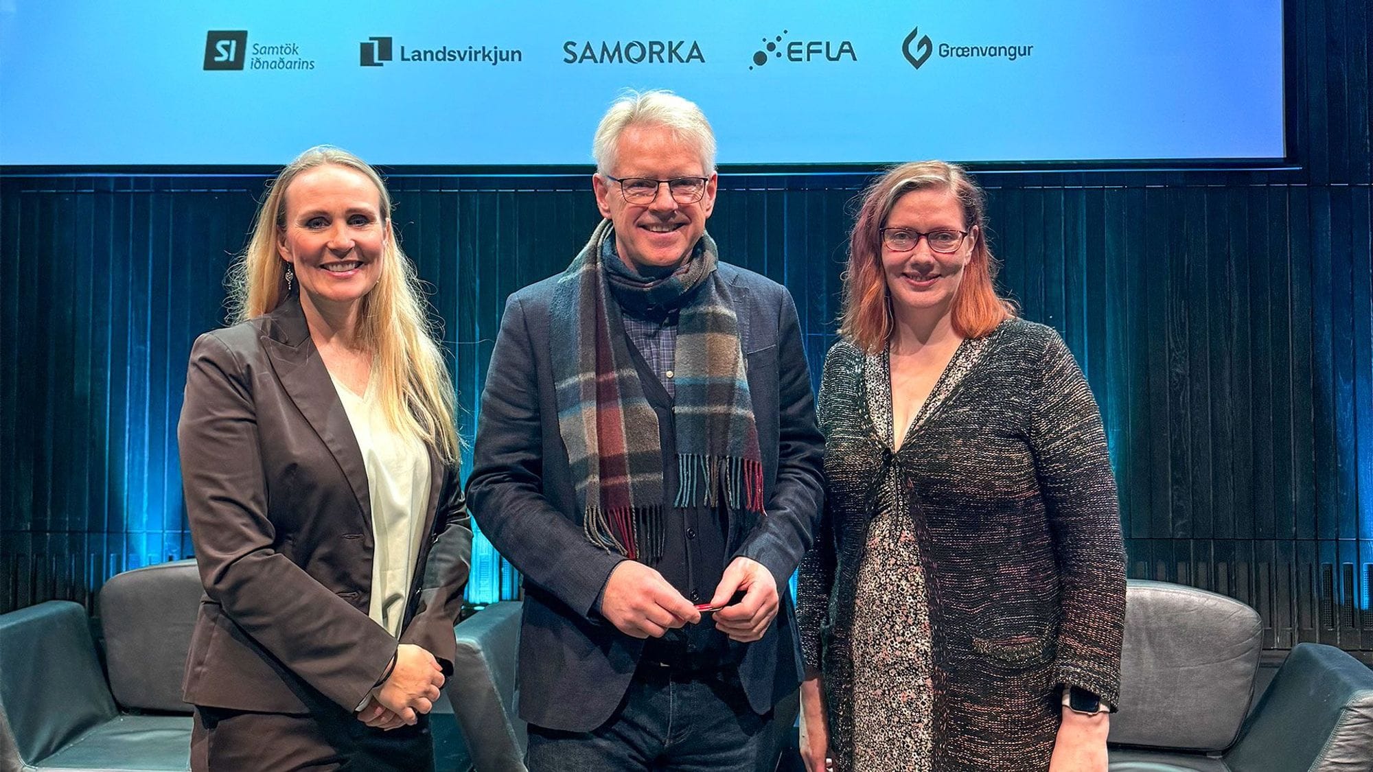 Tvær konur og karl stilla sér upp á sviði eftir fund.