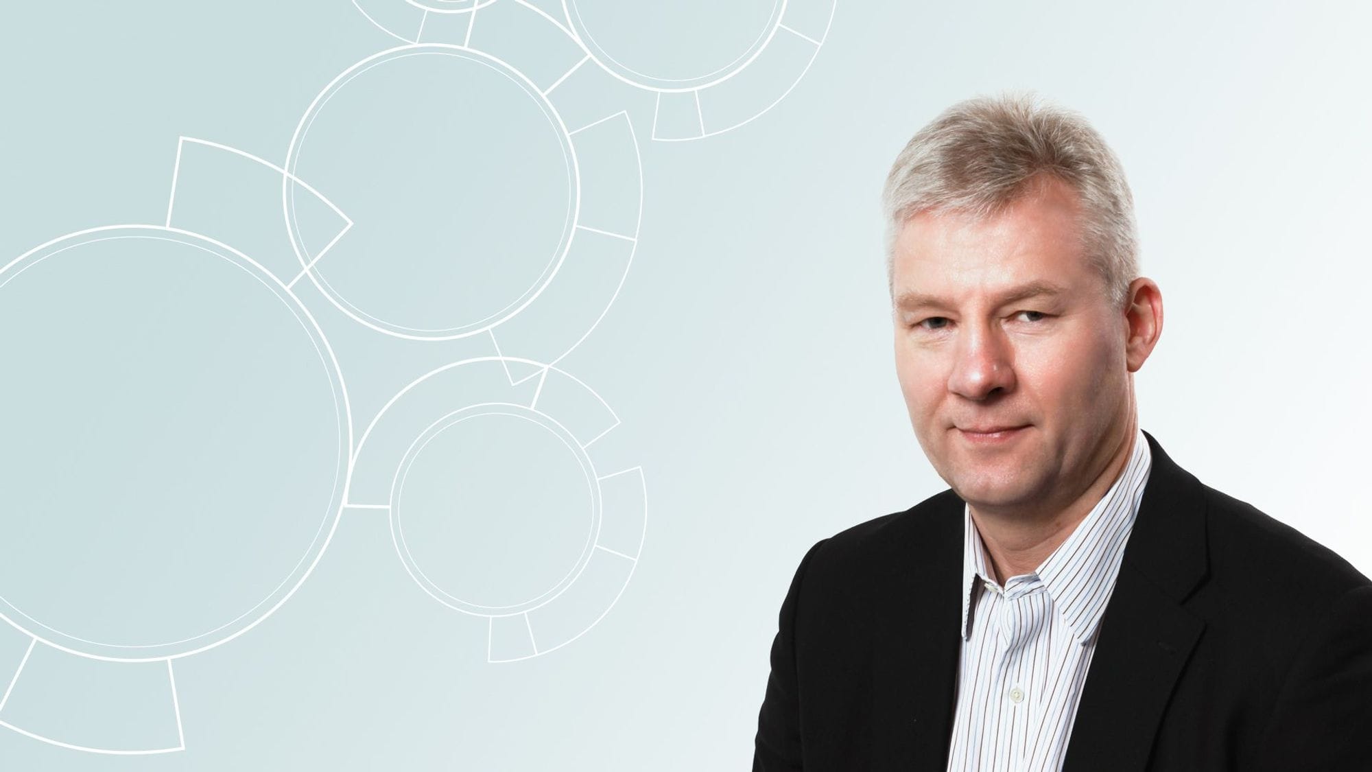 A man in a suit with subtle smile against a background featuring an abstract circular shapes