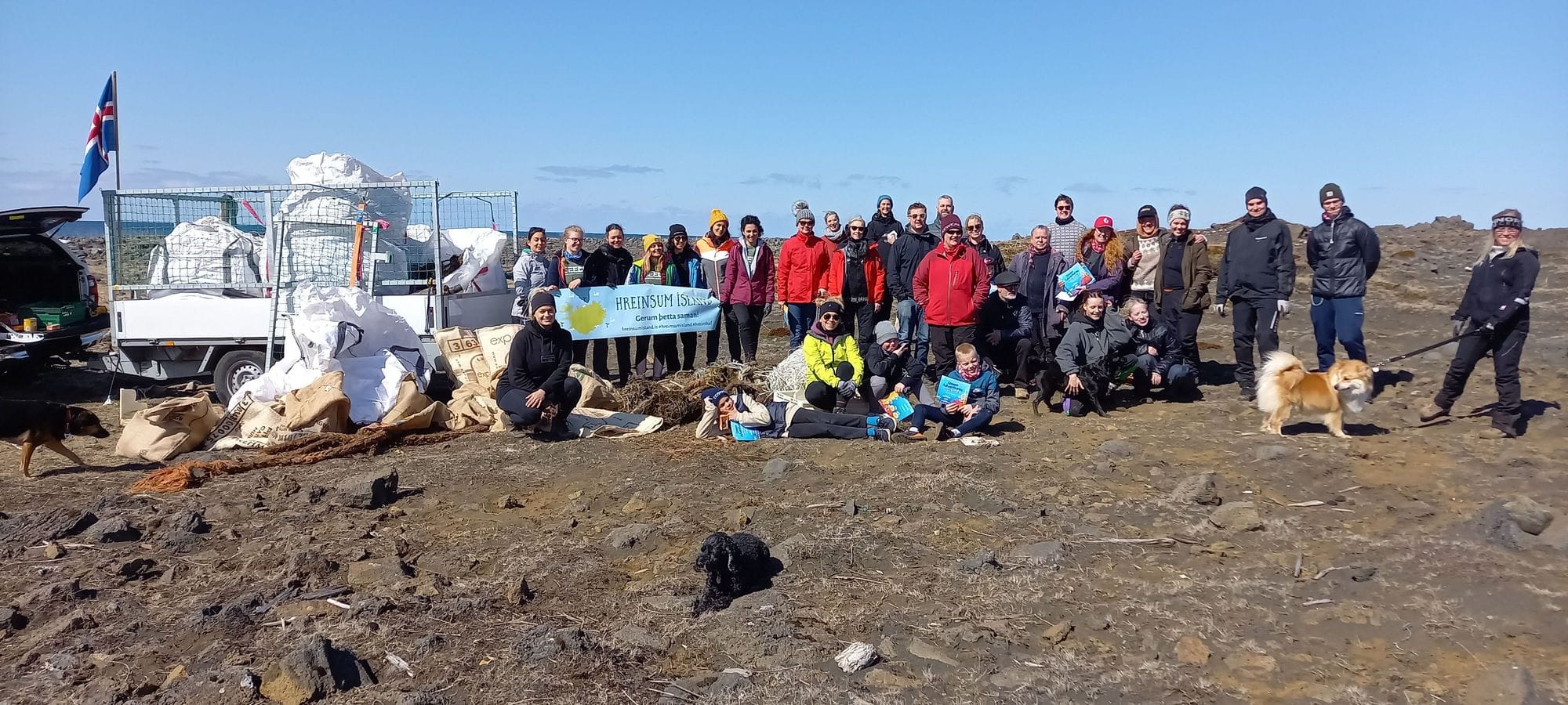 A group of people posing outdoor with a banner reading "HREINSUM ISLAND"