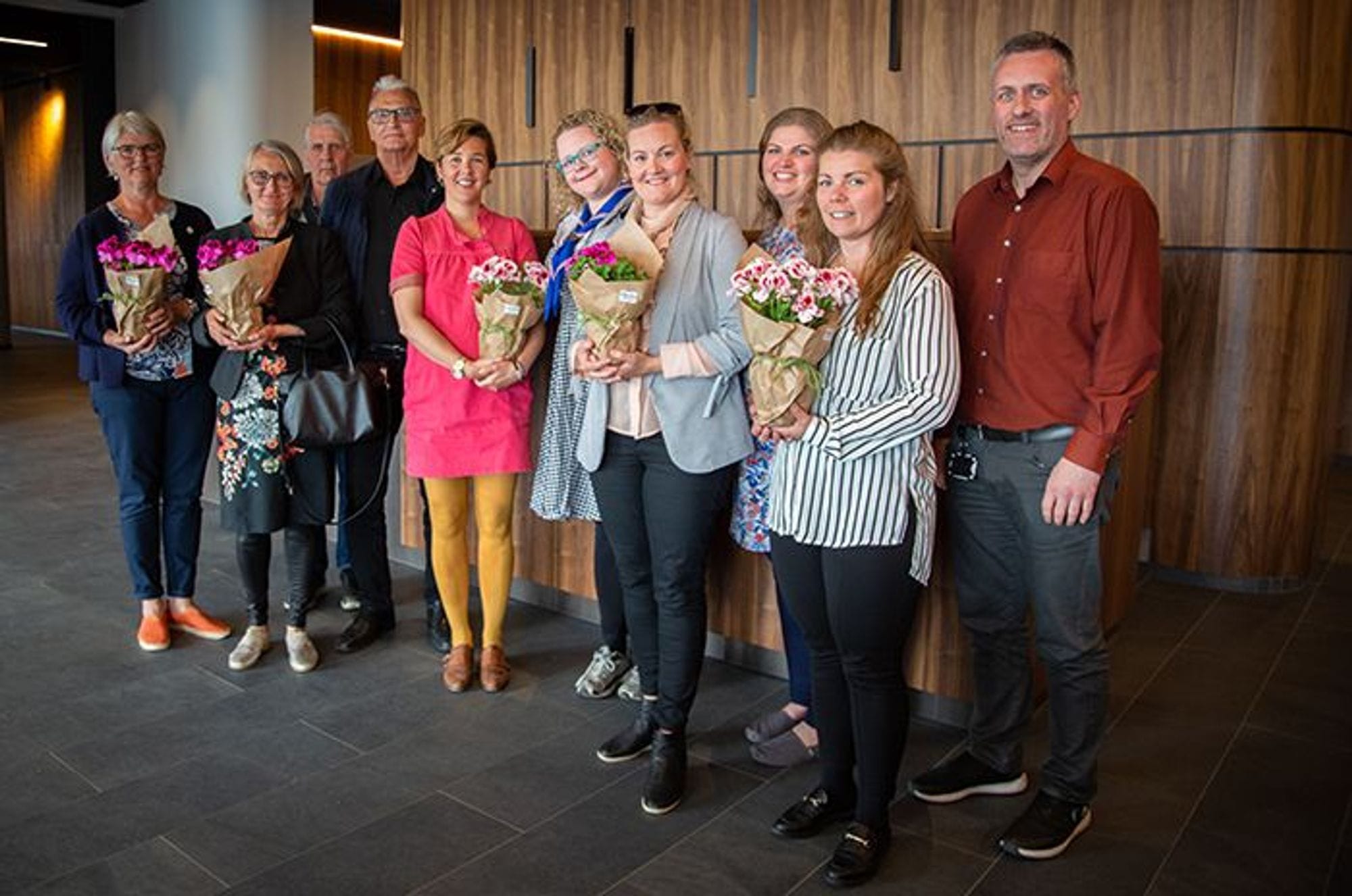 A group of people standing together, holding bouquet of  flowers