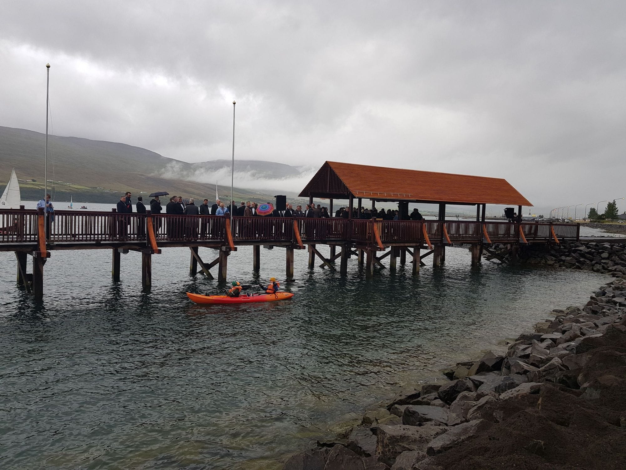 A person in an orange kayak next to a wooden bridge