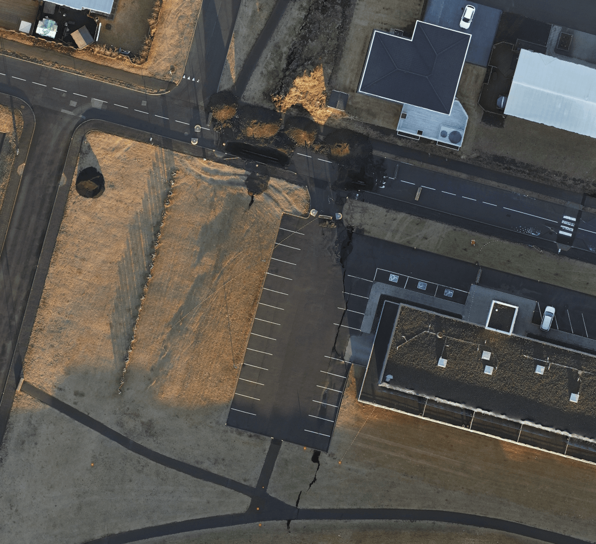 An aerial image focused on a section of a road adjacent to a building with large solar panel 