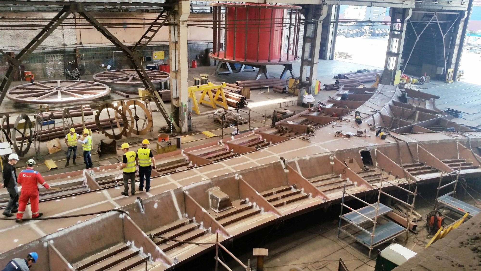 Workers in a large industrial workshop with sections of steel structure