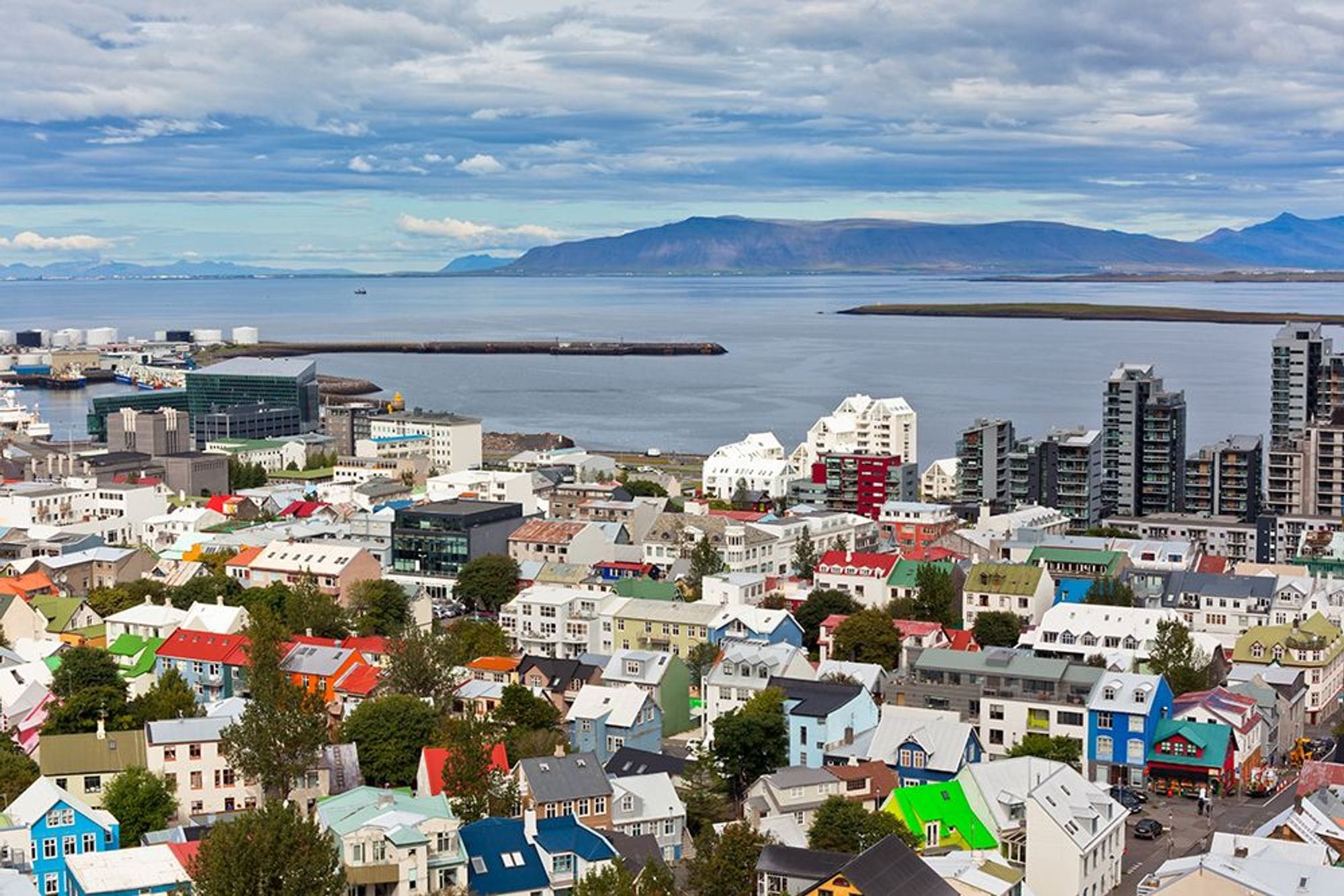 A bird eye view of colorful residential buildings with the ocean and mountainous landscape background
