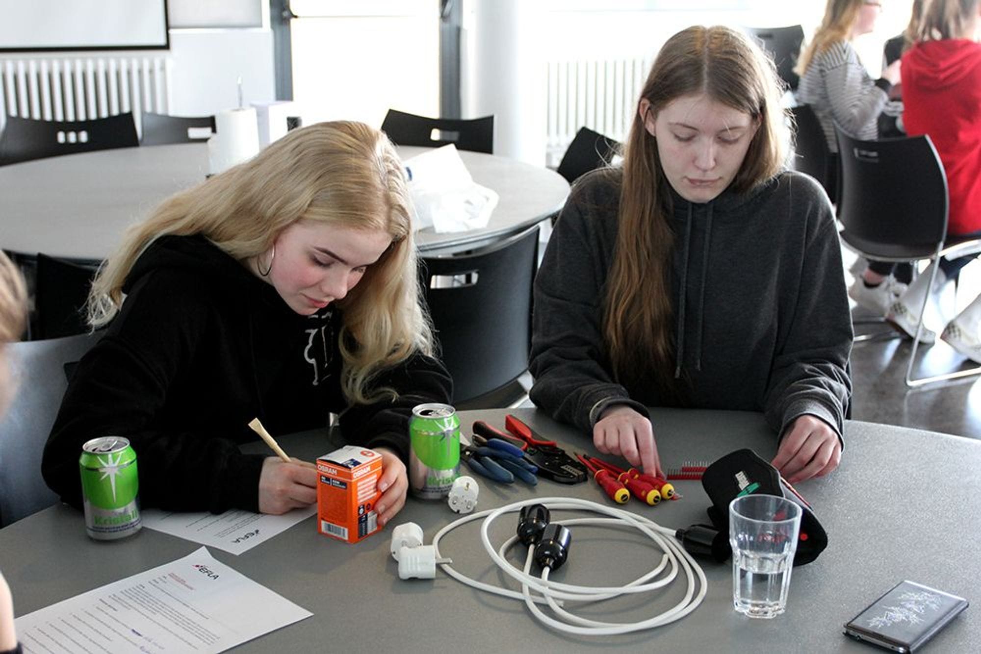 Two girls organizing tools and writing on a table