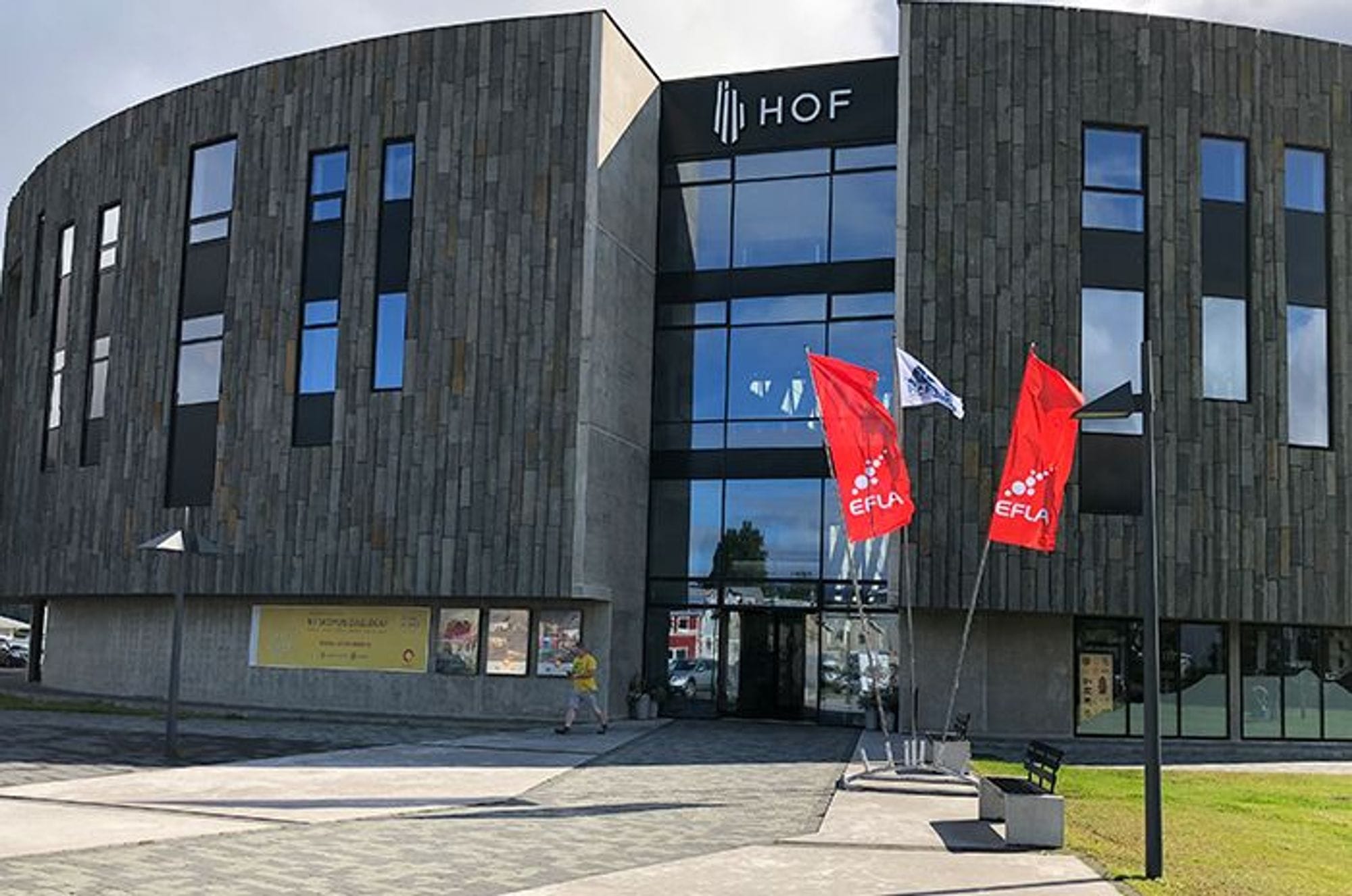 A modern building with two red flag in front, under a clear sky