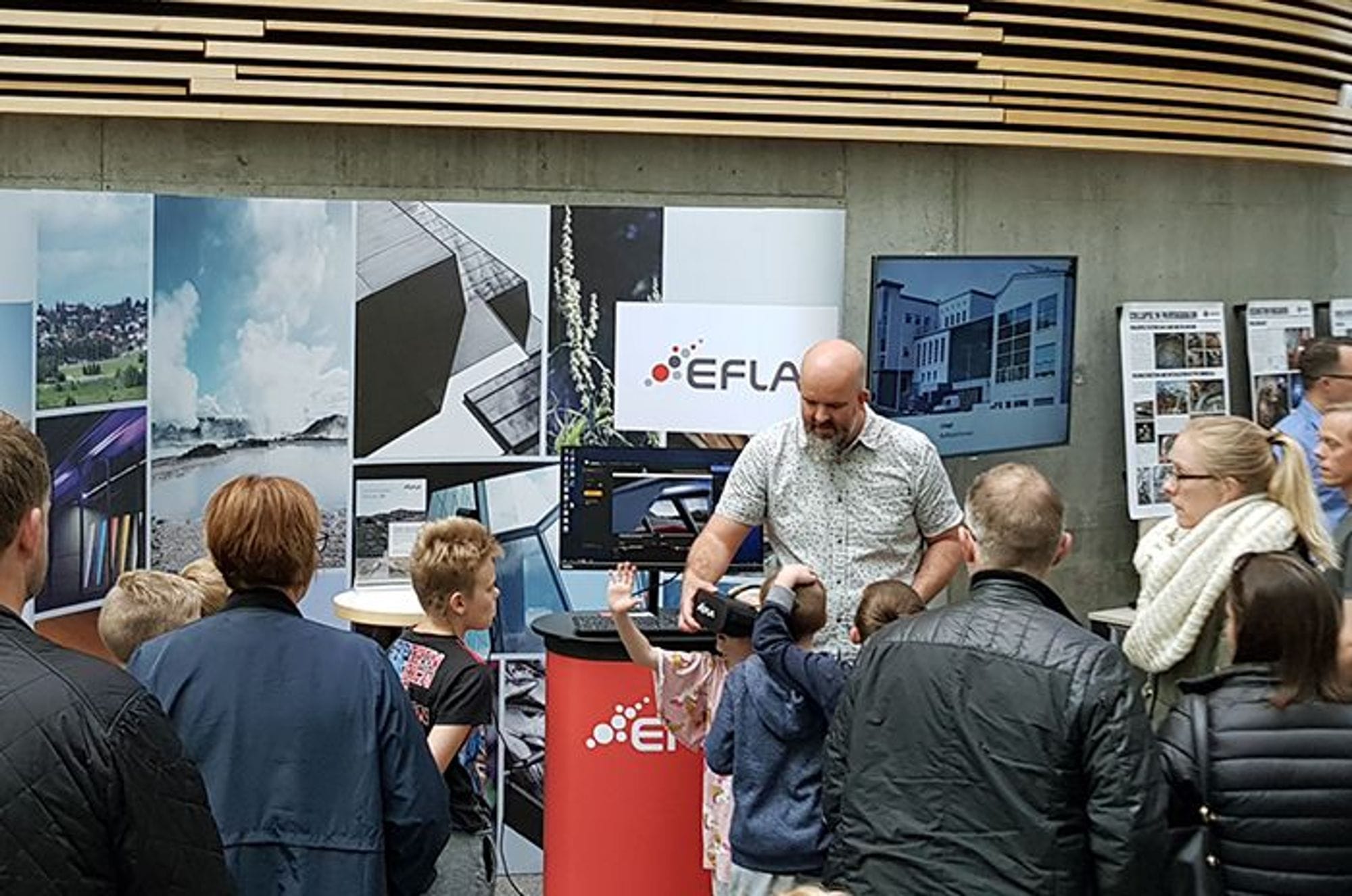 A man presenting at an exhibition booth with an audience