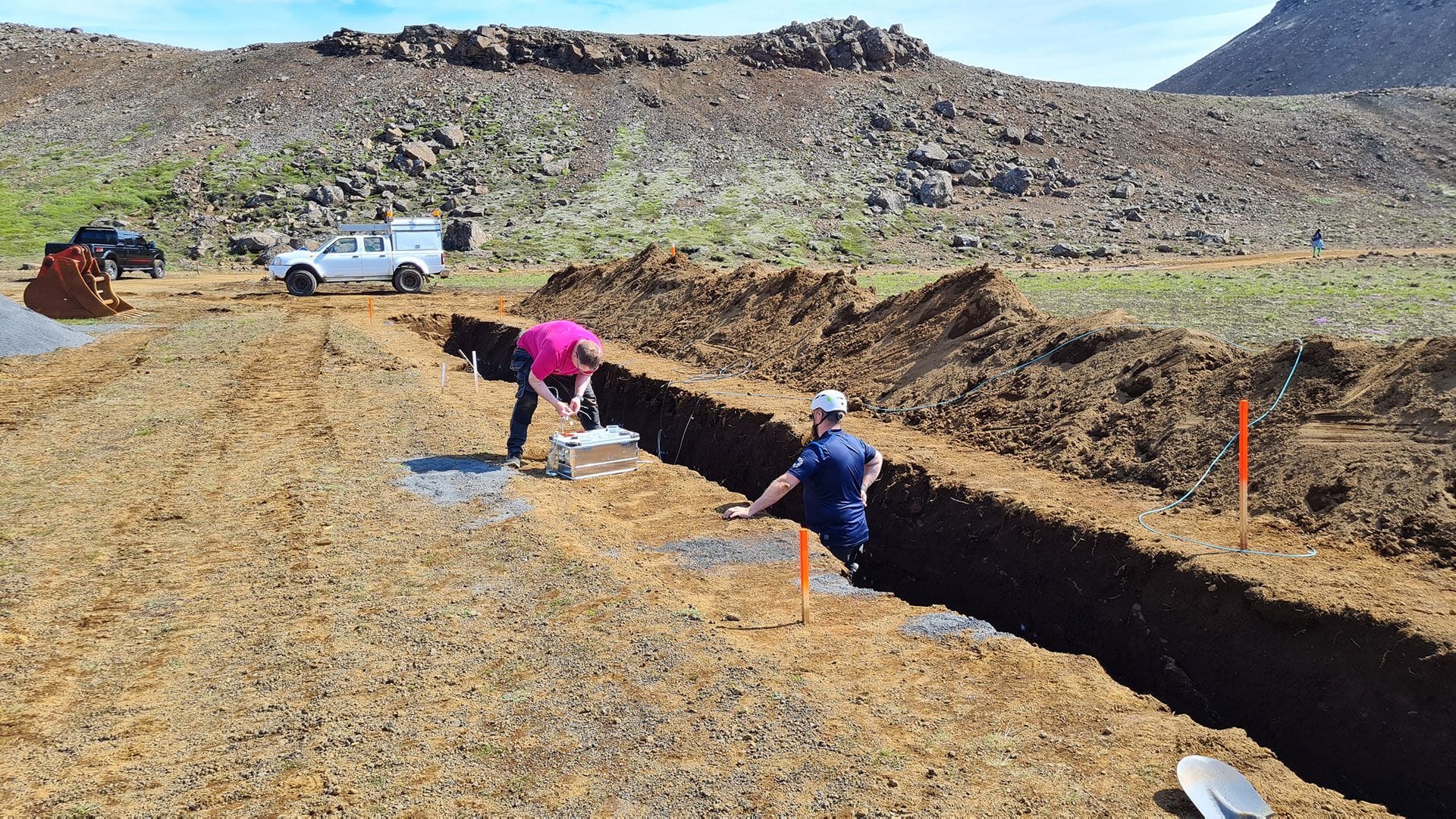 Two men working in a large open excavation site 