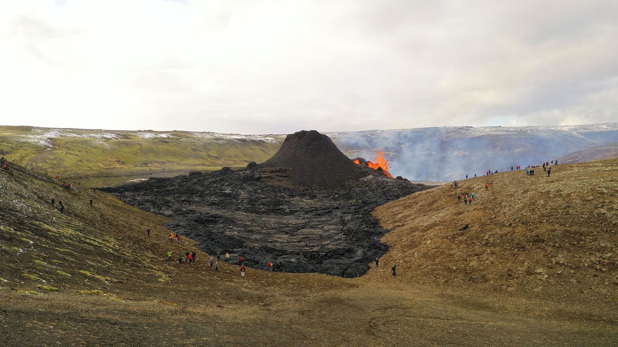 People observing an active volcano eruption with a lava fountain