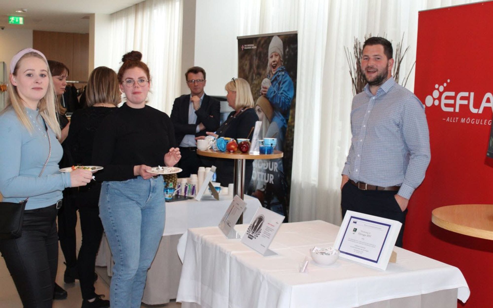 Several individuals gathered around a table with informational material displayed